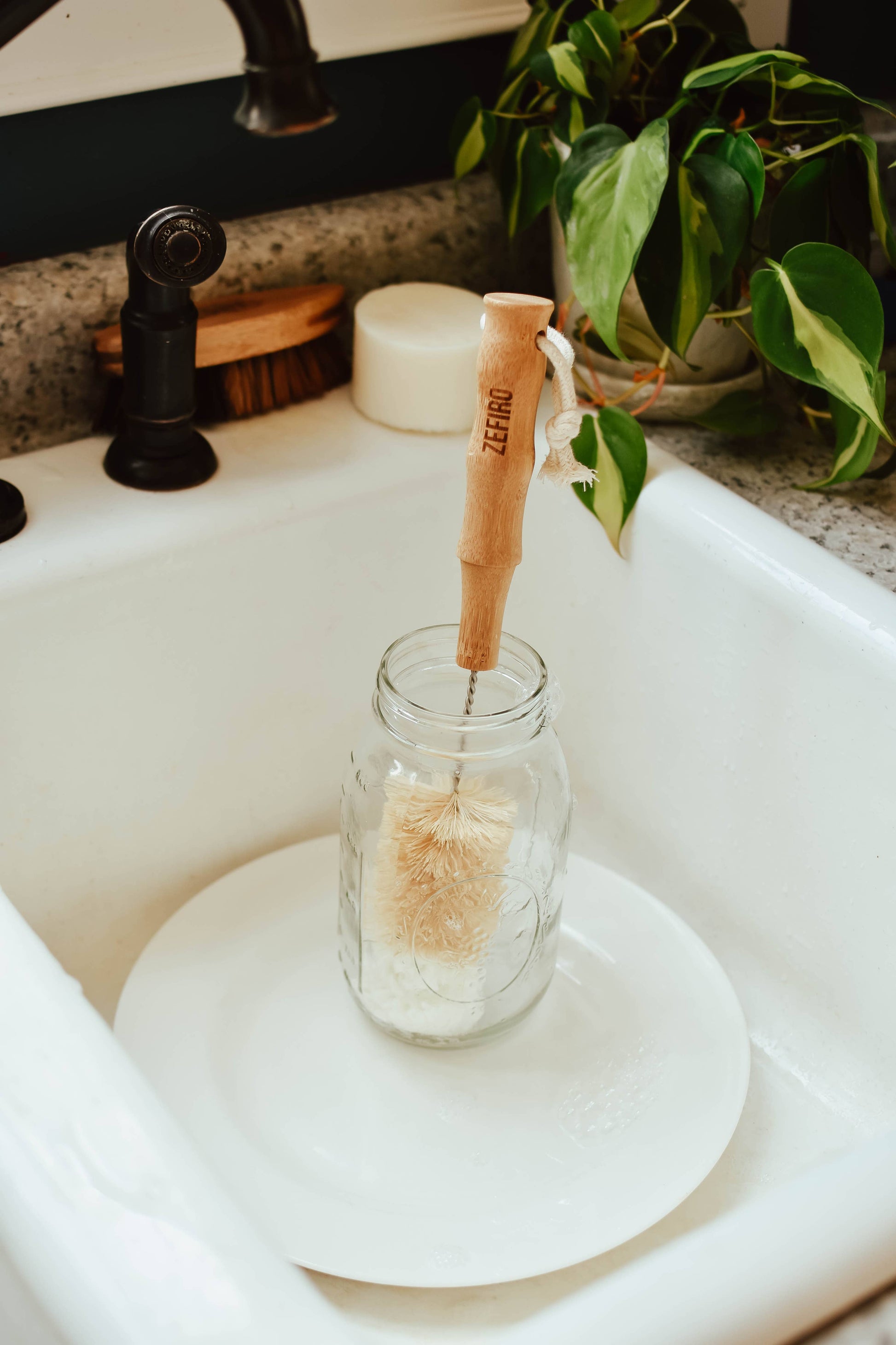 Glass jar with a wooden scrubber inside on a white sink