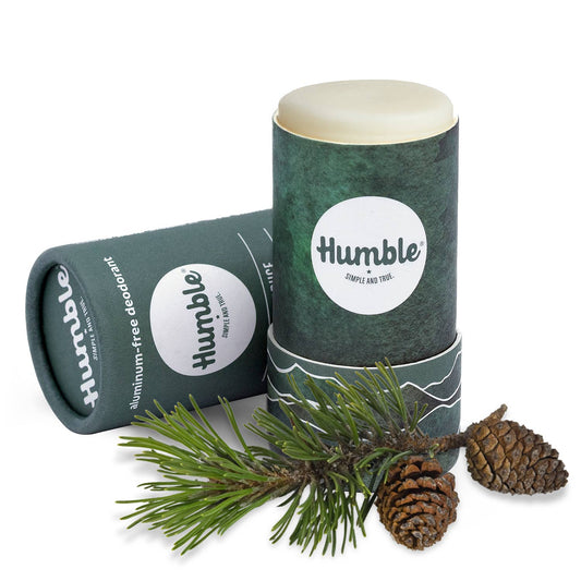 Two 'humble' aluminum-free deodorant sticks with a branch and pine cones on a white background