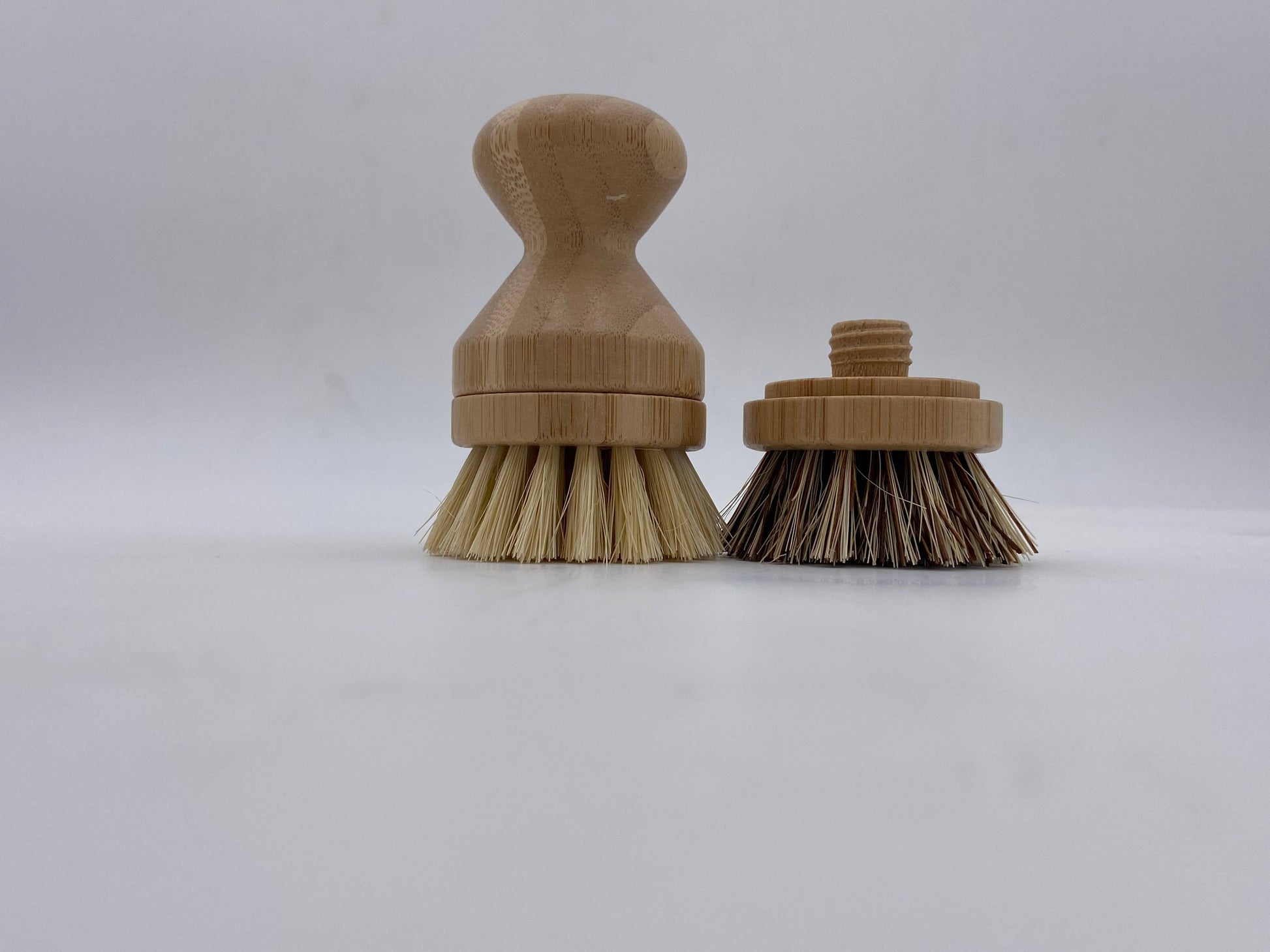 Two bamboo scrub brushes with bristle heads on a white background