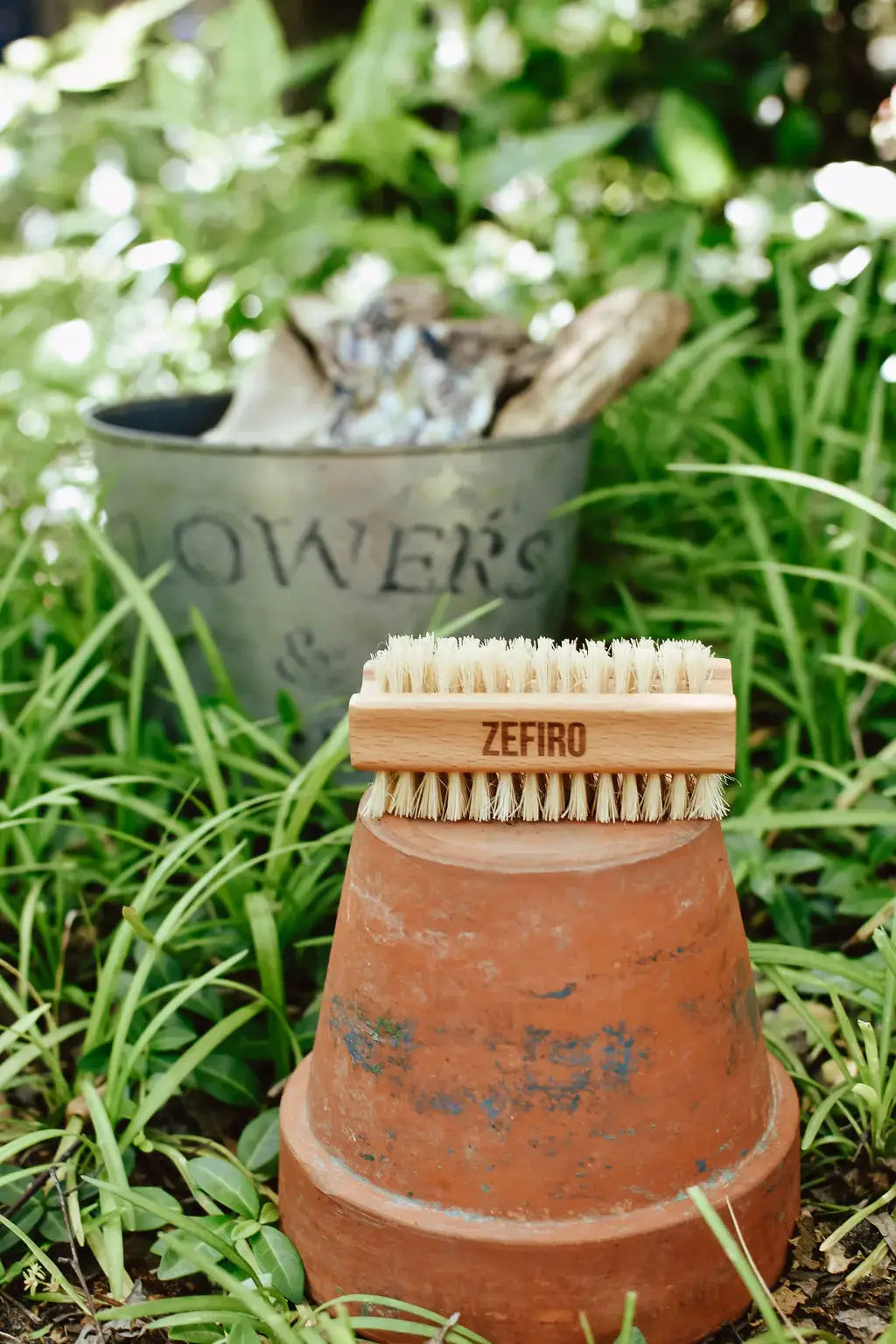Branding tool with 'Zefiro' logo on a terracotta pot in a garden setting
