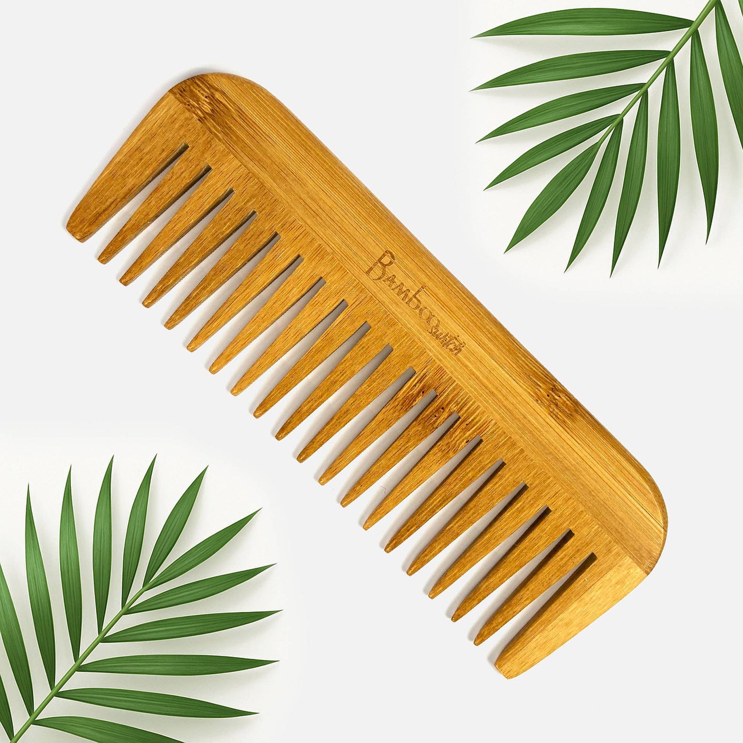 Bamboo comb with green leaves on a white background