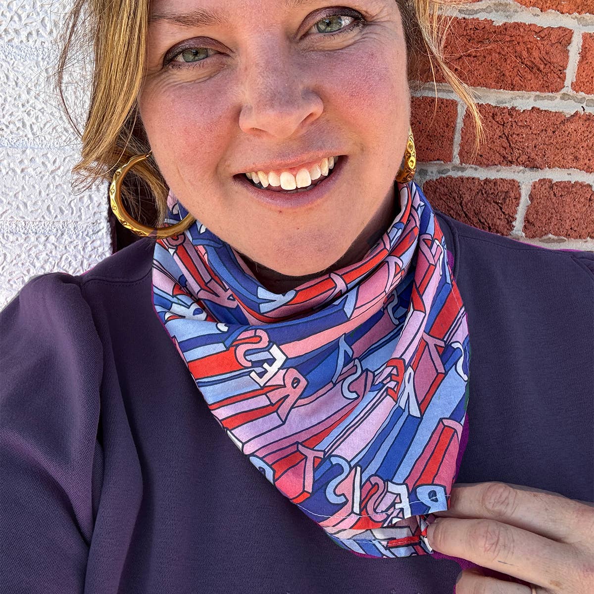 Woman wearing a colorful scarf with a brick wall background