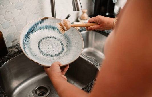 Person washing a ceramic plate in a kitchen sink