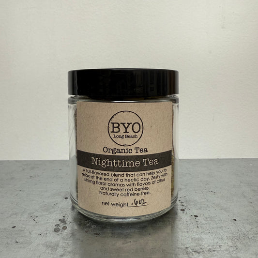 Glass jar of Organic Tea Nighttime Tea with a black lid on a gray surface.