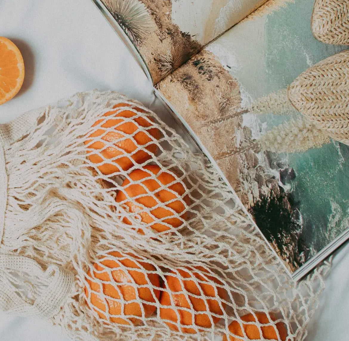 String market bag with oranges on a white background next to a book.