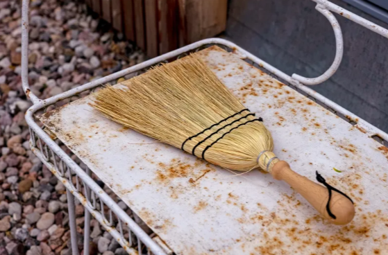 Straw broom laying on outdoor bench