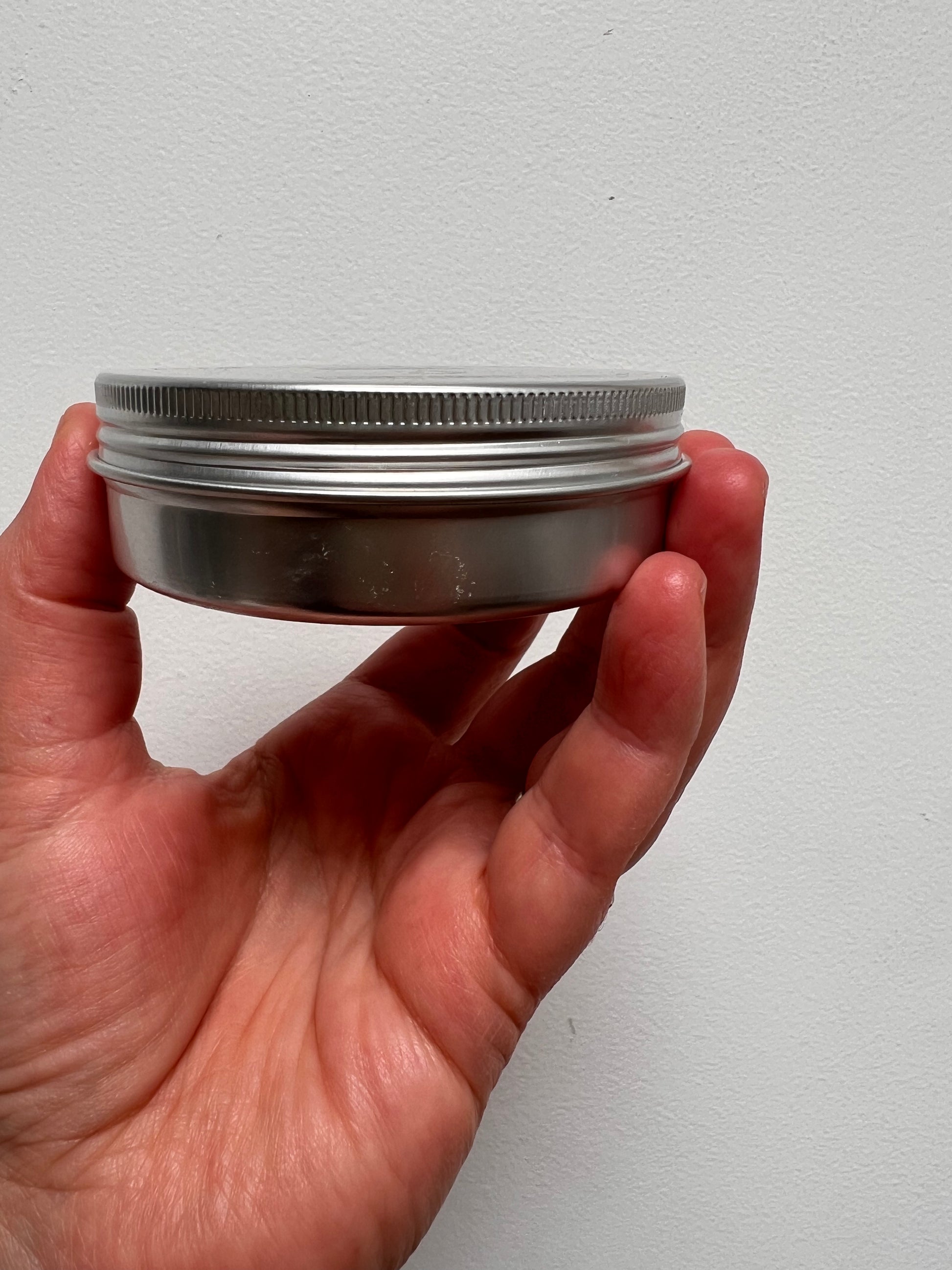 Side profile of tin showing the threading of the lid to unscrew top.