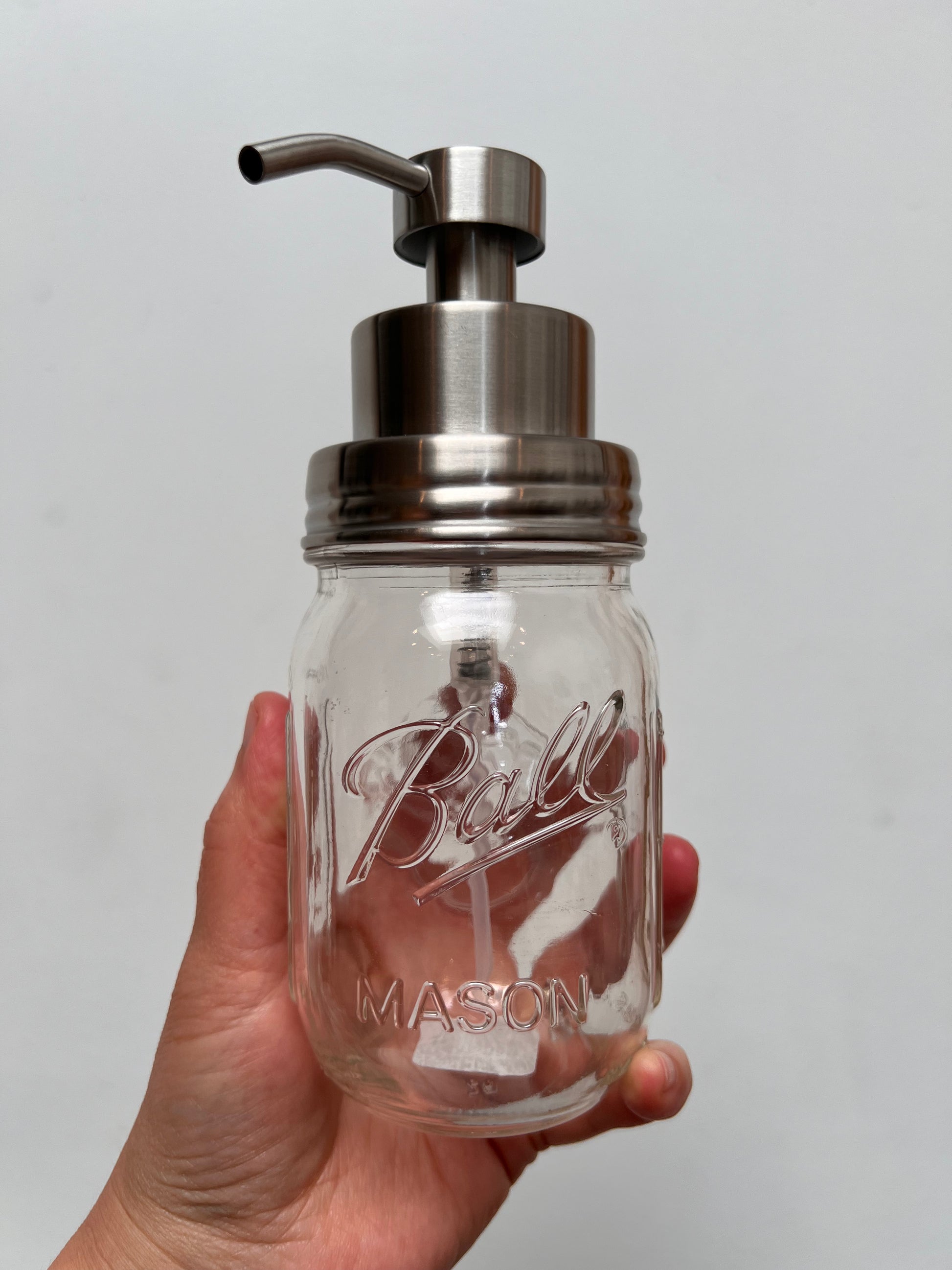 Hand holding pint mason jar with stainless steel foaming top