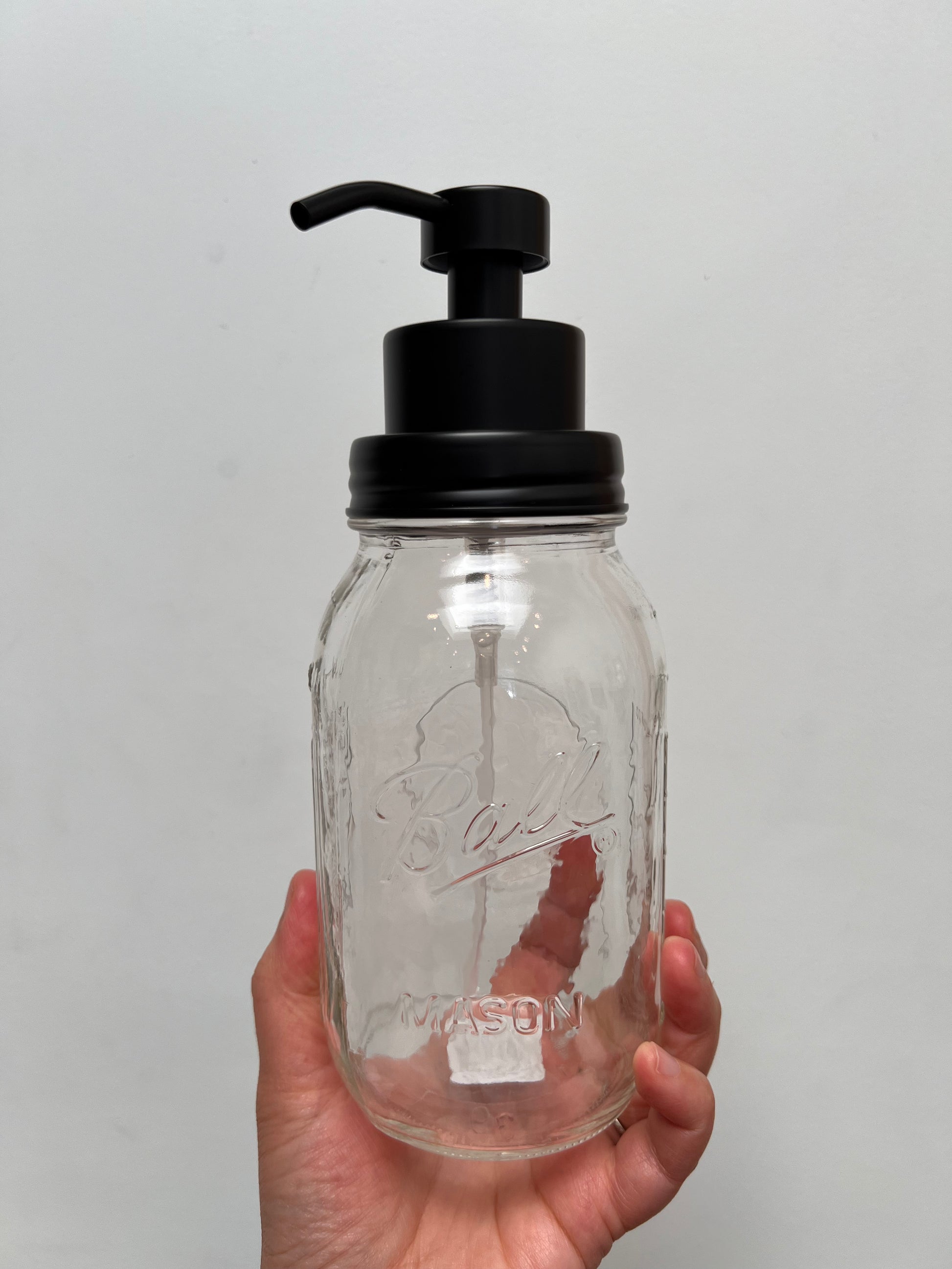 Hand holding quart mason jar with black finish foaming top
