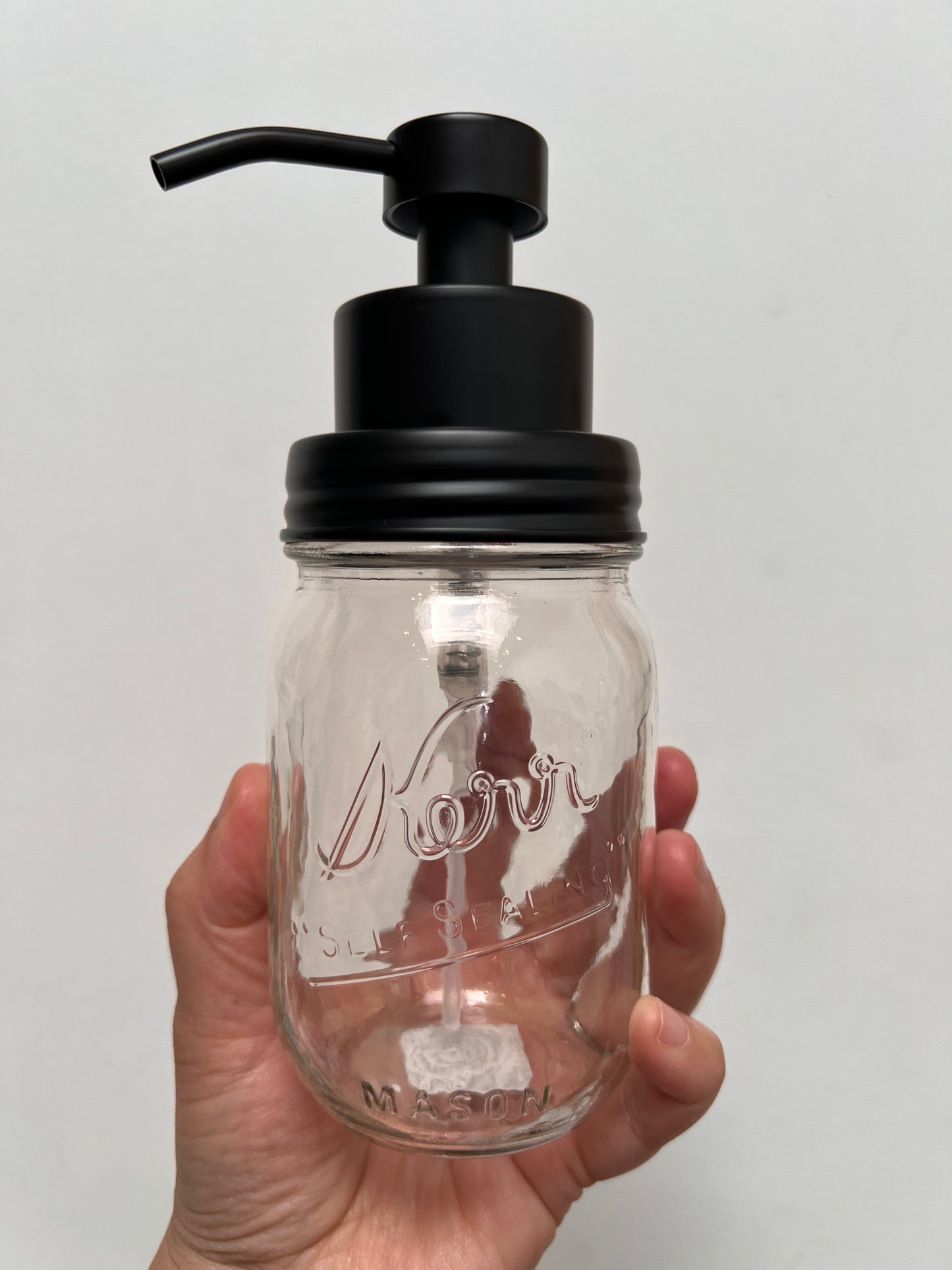 Hand holding pint mason jar with black finish foaming top