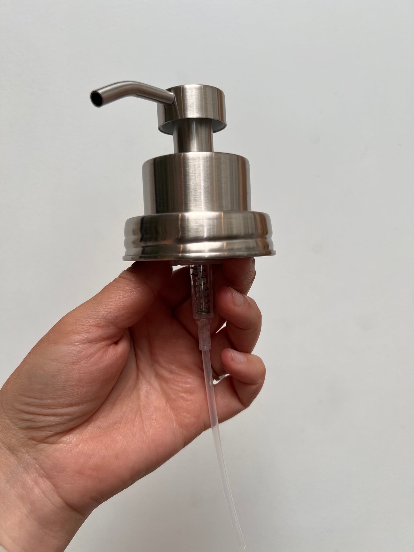 Hand holding stainless steel foaming top without jar