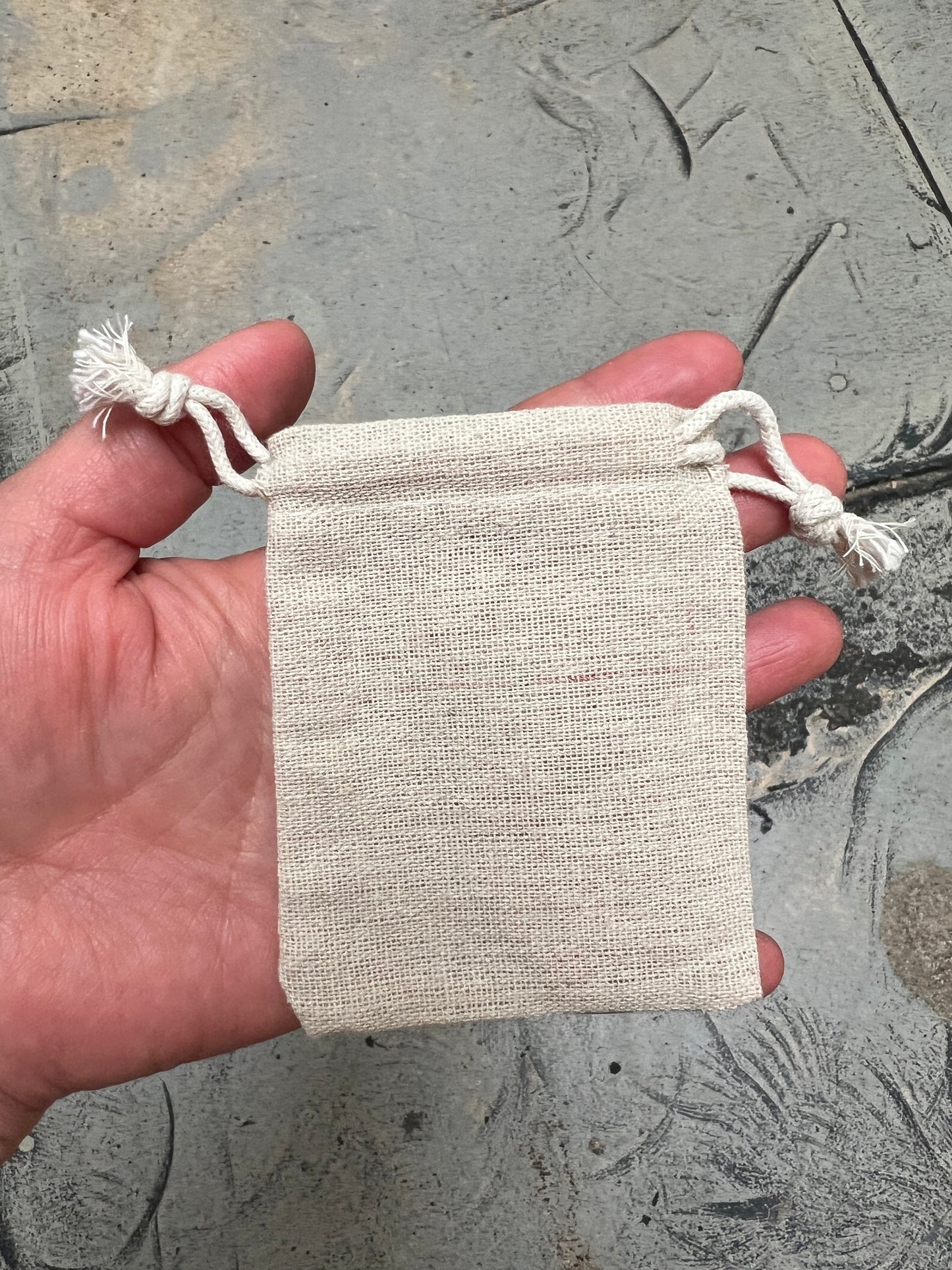 Hand holding cotton drawstring pouch without spork.
