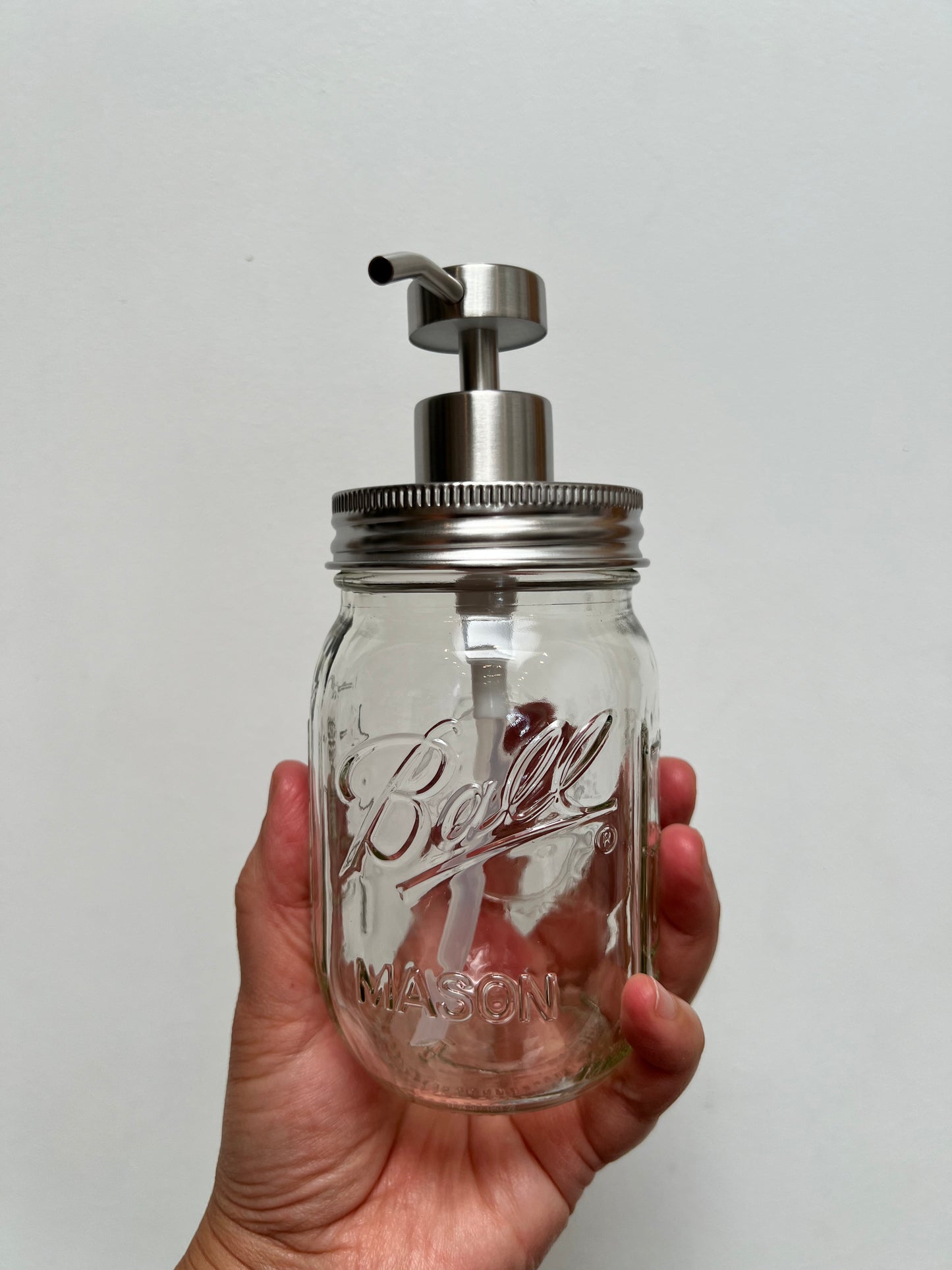 Hand holding pint mason jar with stainless steel regular pump top