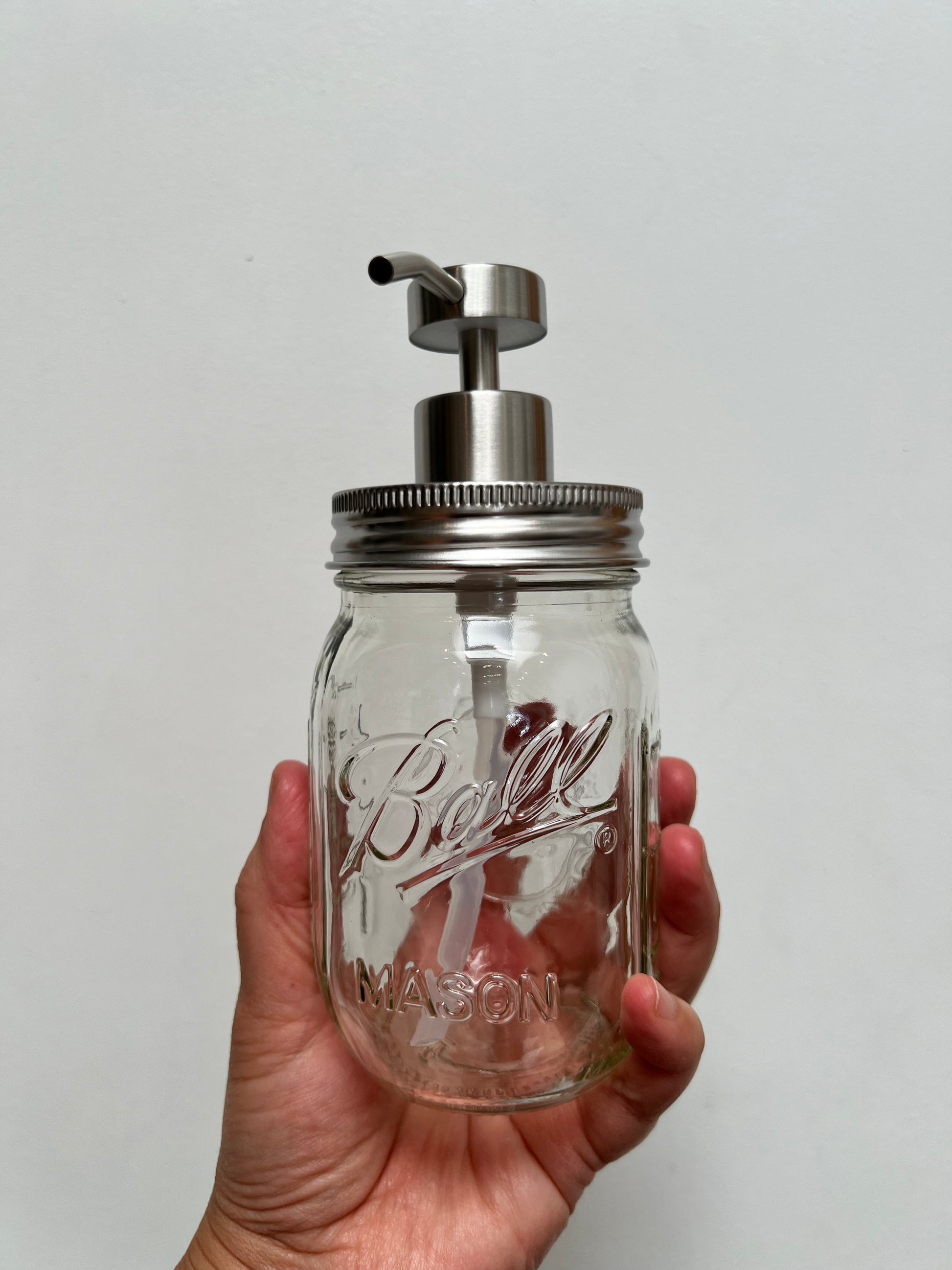 Hand holding pint mason jar with stainless steel regular pump top