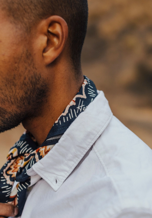 Close-up of a person wearing a patterned shirt and white jacket with a blurred background