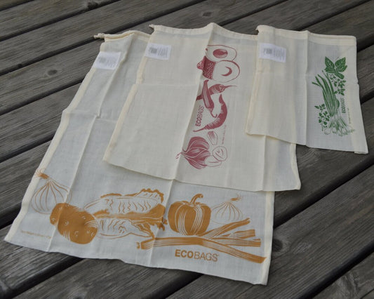 Set of 3 reusable produce bags. Each bag is a light cotton gauze with a printed image. 3 pack includes a small, medium, and large bag, displayed on a gray wood background.