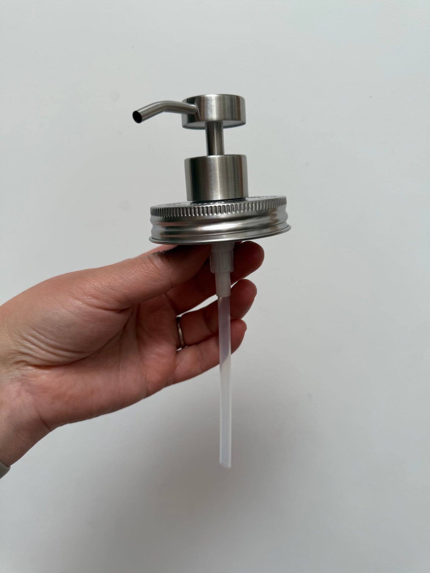 Hand holding stainless steel regular mouth pump top without jar