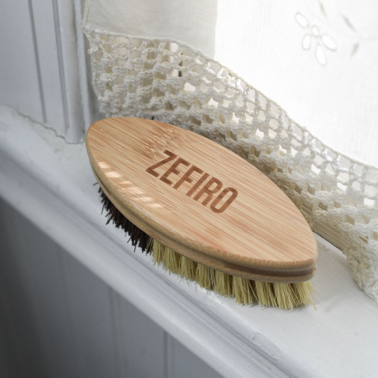 Wooden brush with bristles on a white surface, branded 'Zefiro'.