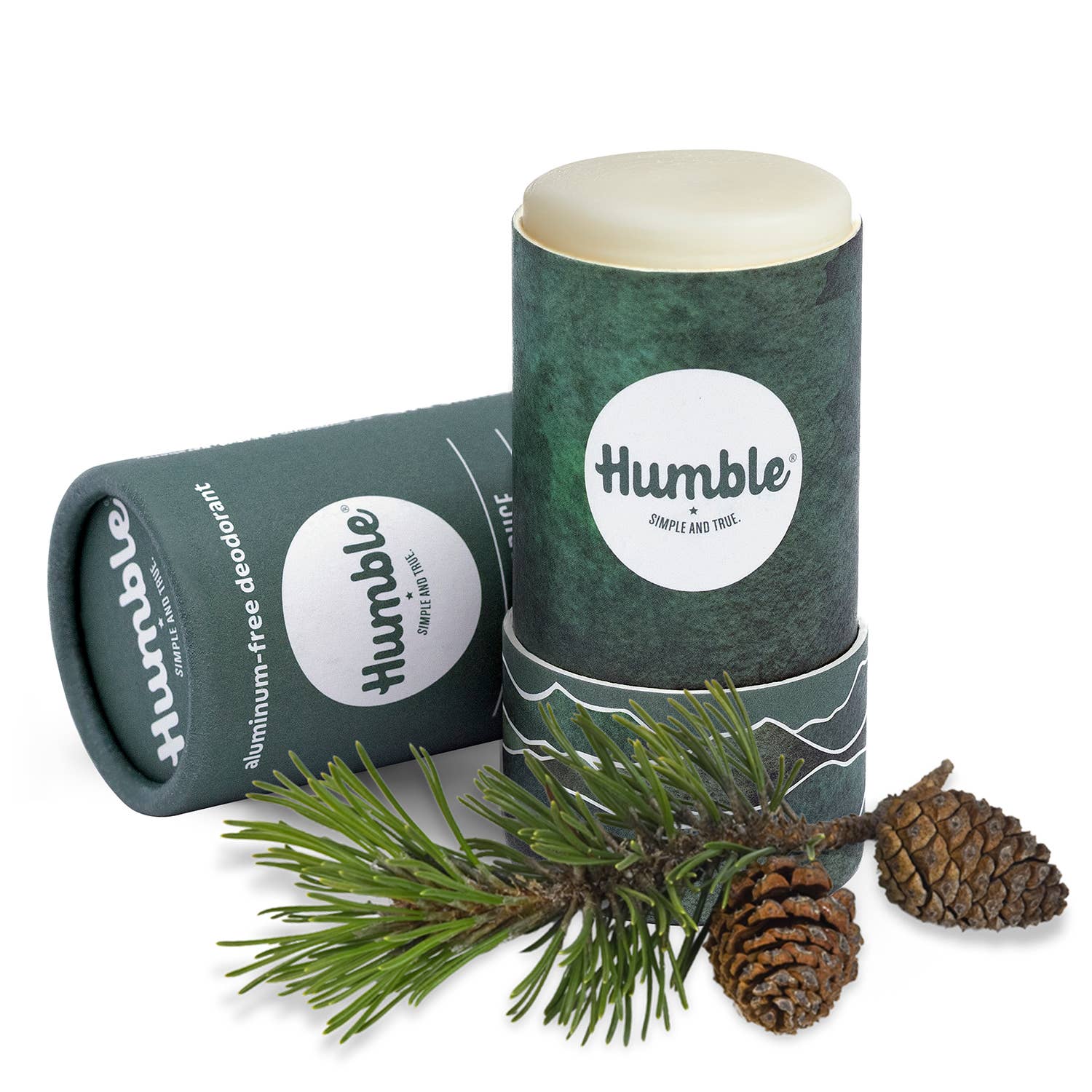 Two 'humble' aluminum-free deodorant sticks with a branch and pine cones on a white background