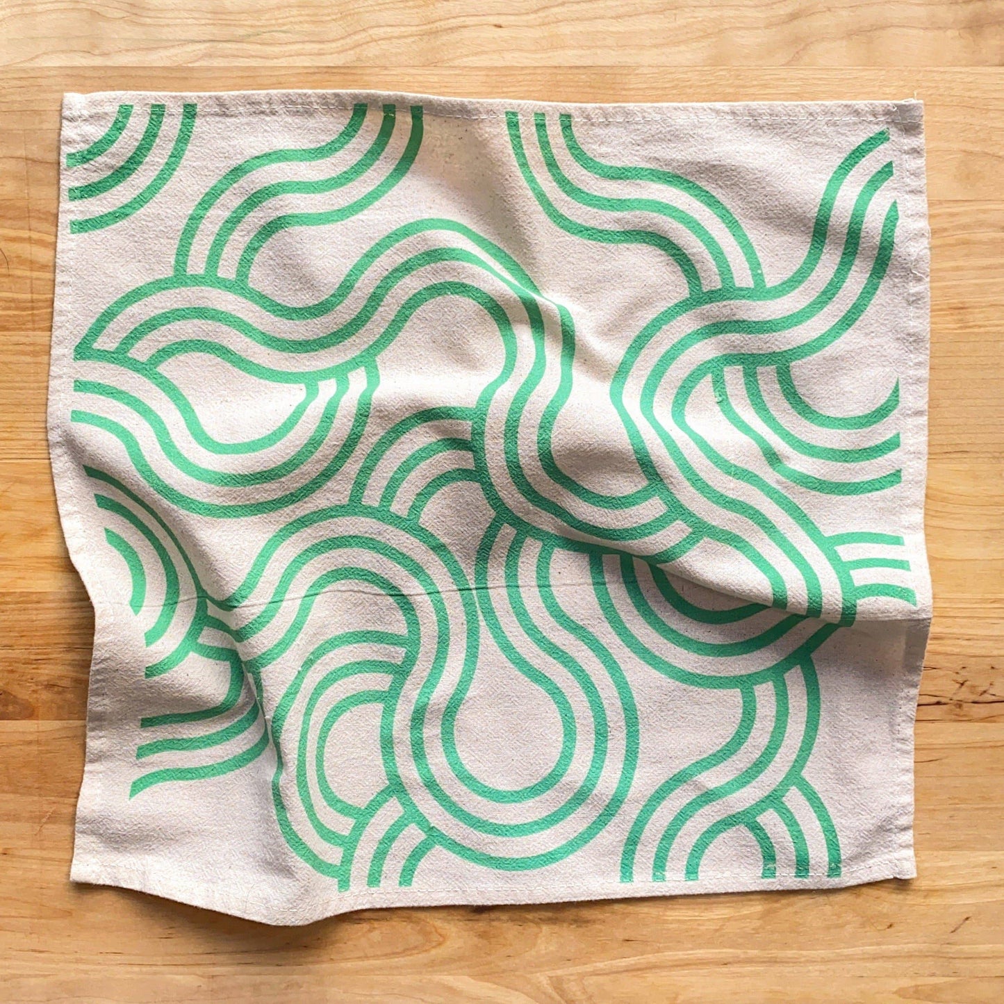 Fabric with green wavy pattern on a wooden surface