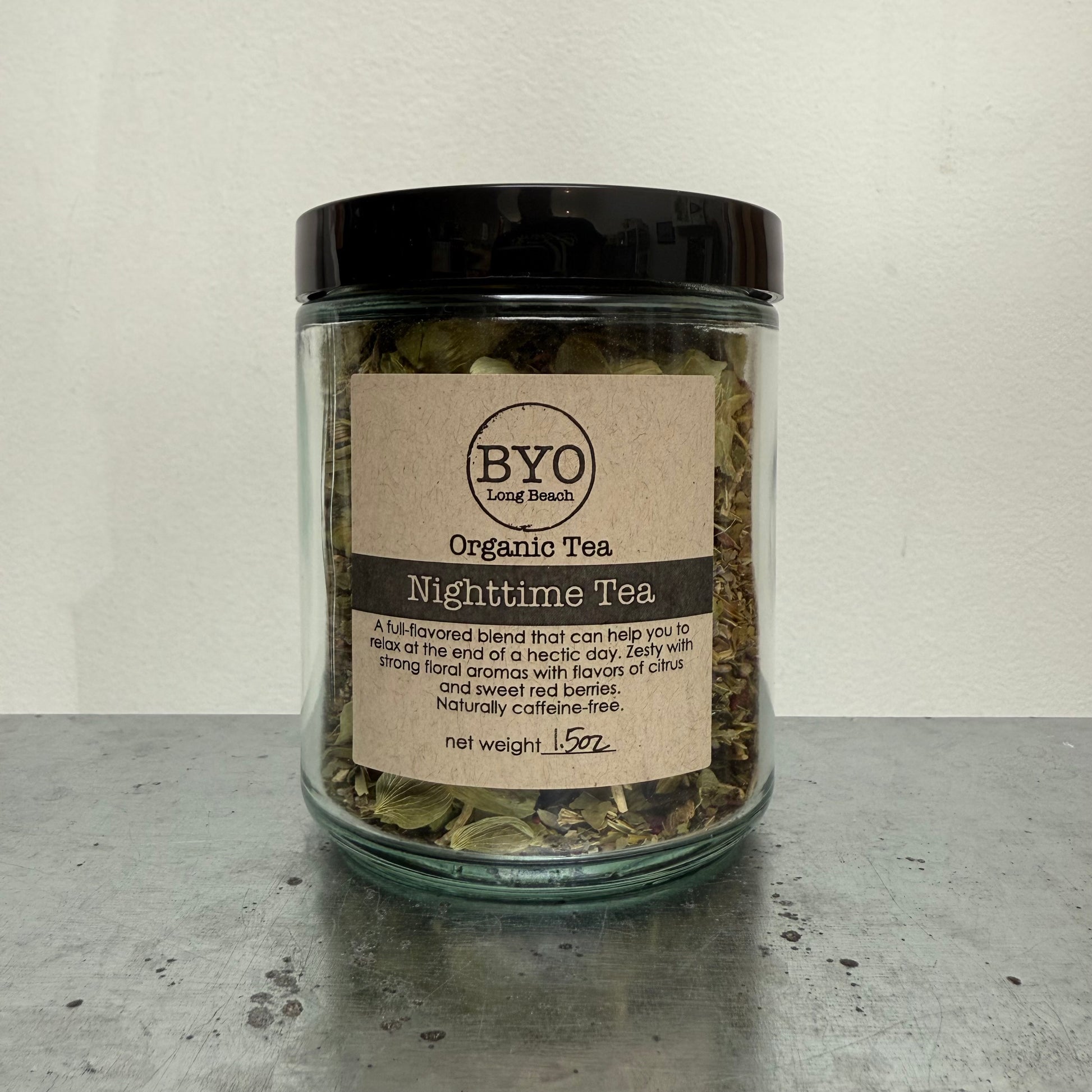 Glass jar of organic nighttime tea with a black lid on a gray surface.