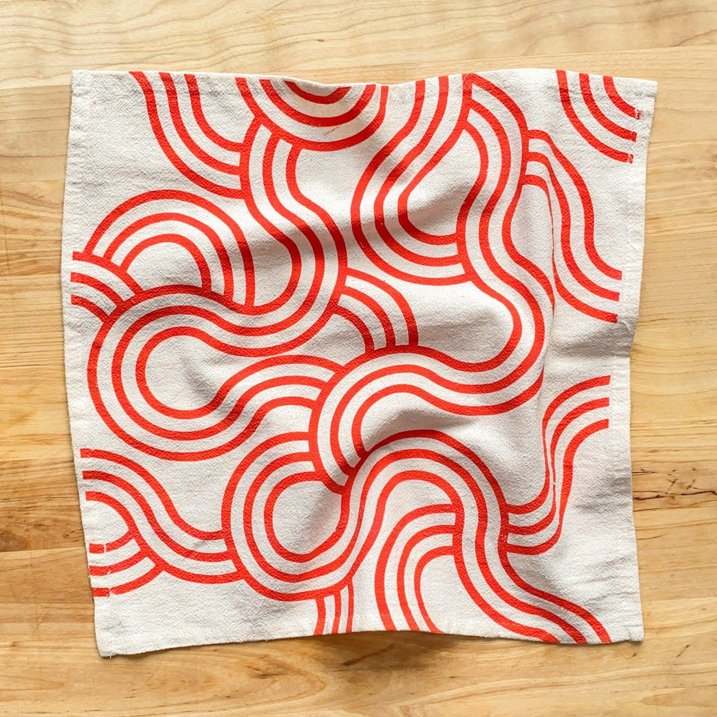 Fabric with red wavy pattern on a wooden surface