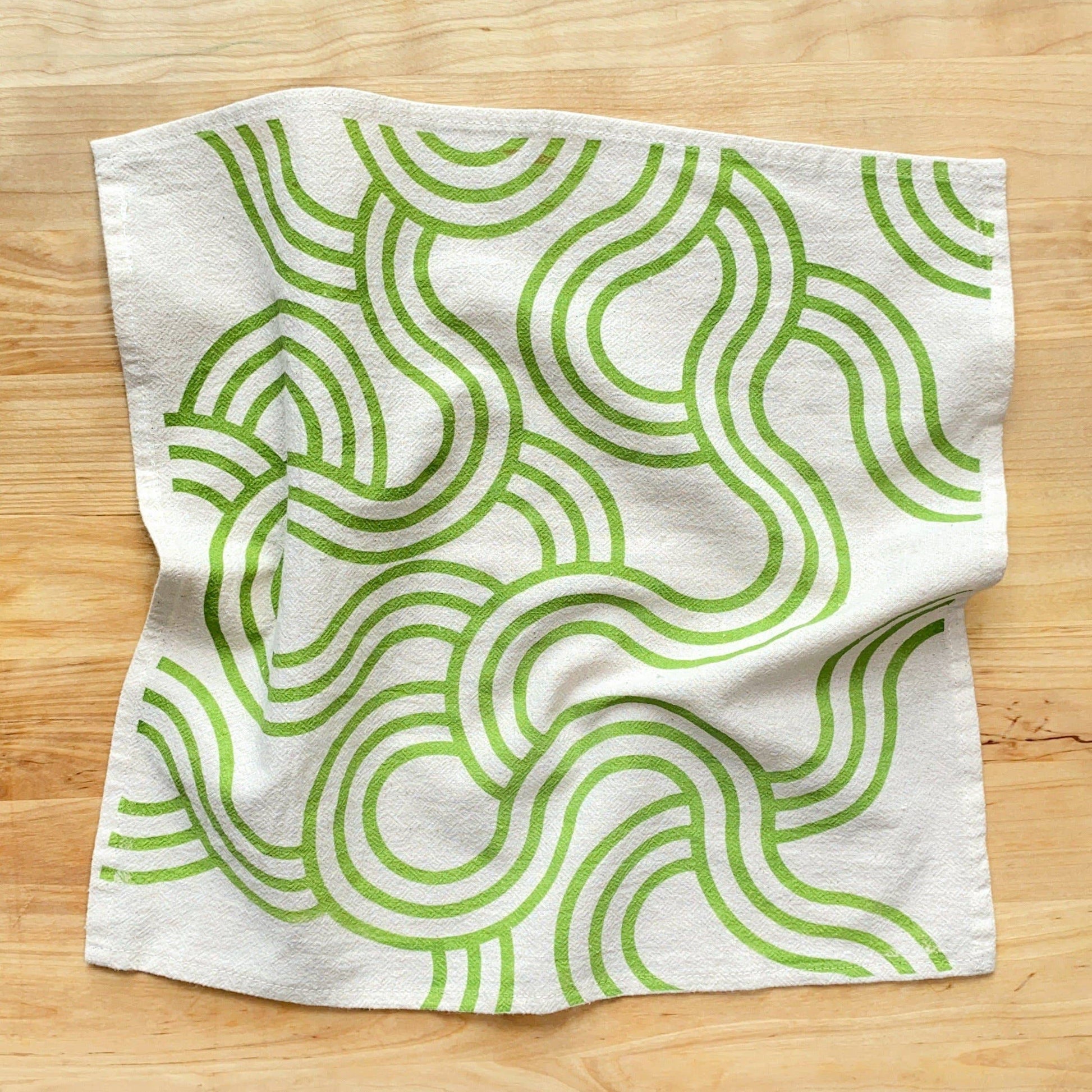 Fabric with green wave pattern on a wooden surface