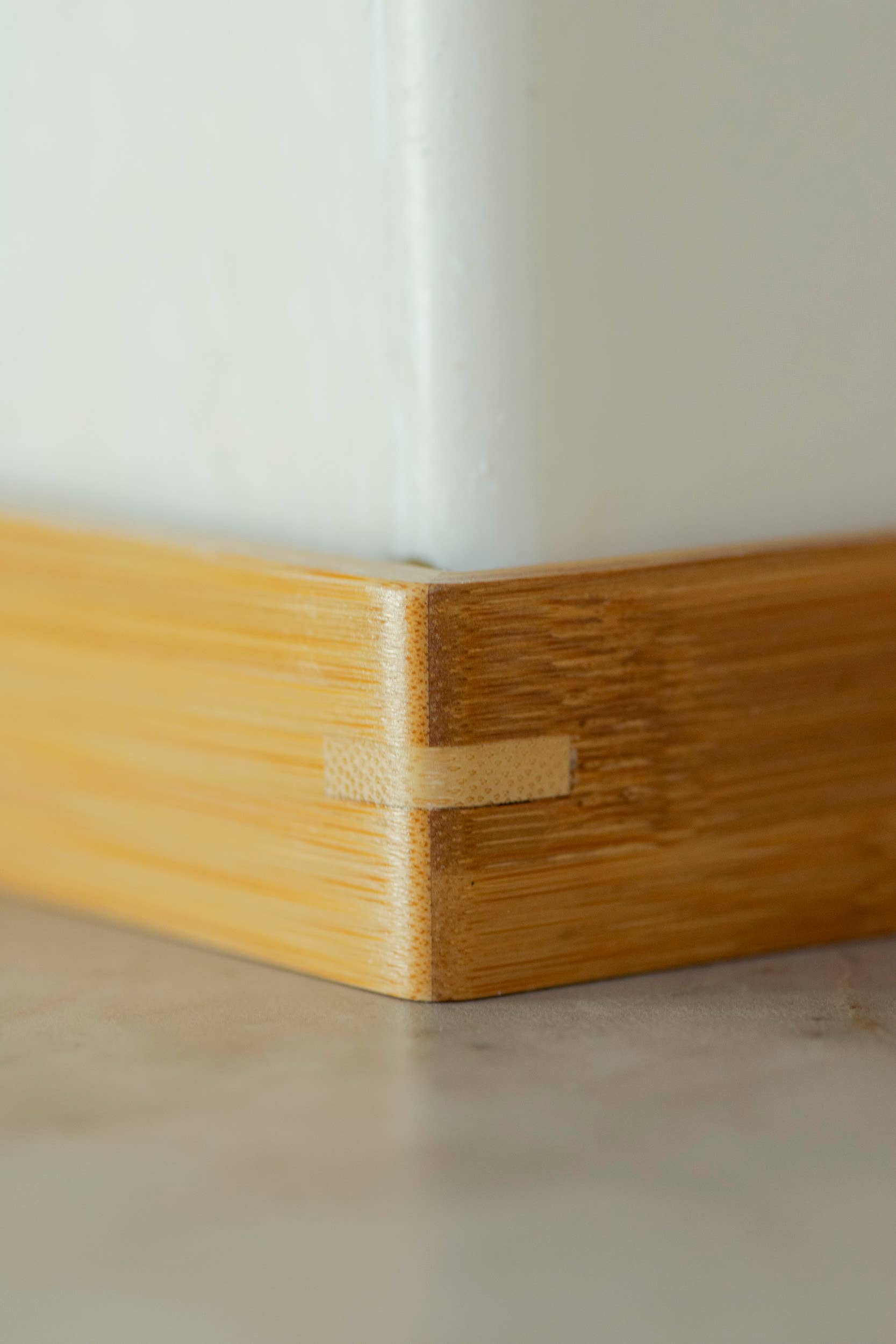 Close-up of a wooden cutting board with a visible joint on a neutral background