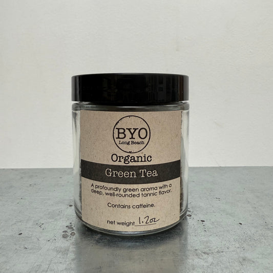 Jar of organic green tea with a black lid on a gray surface
