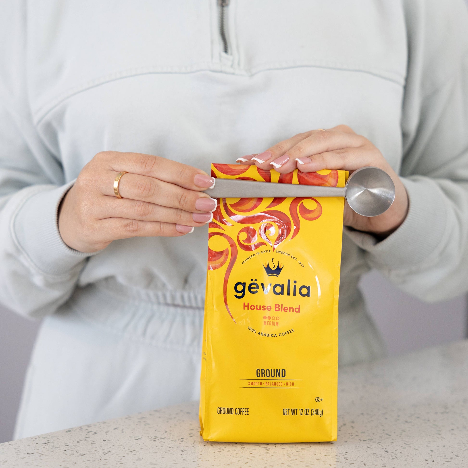 Person opening a Gevalia coffee package with a knife on a neutral background