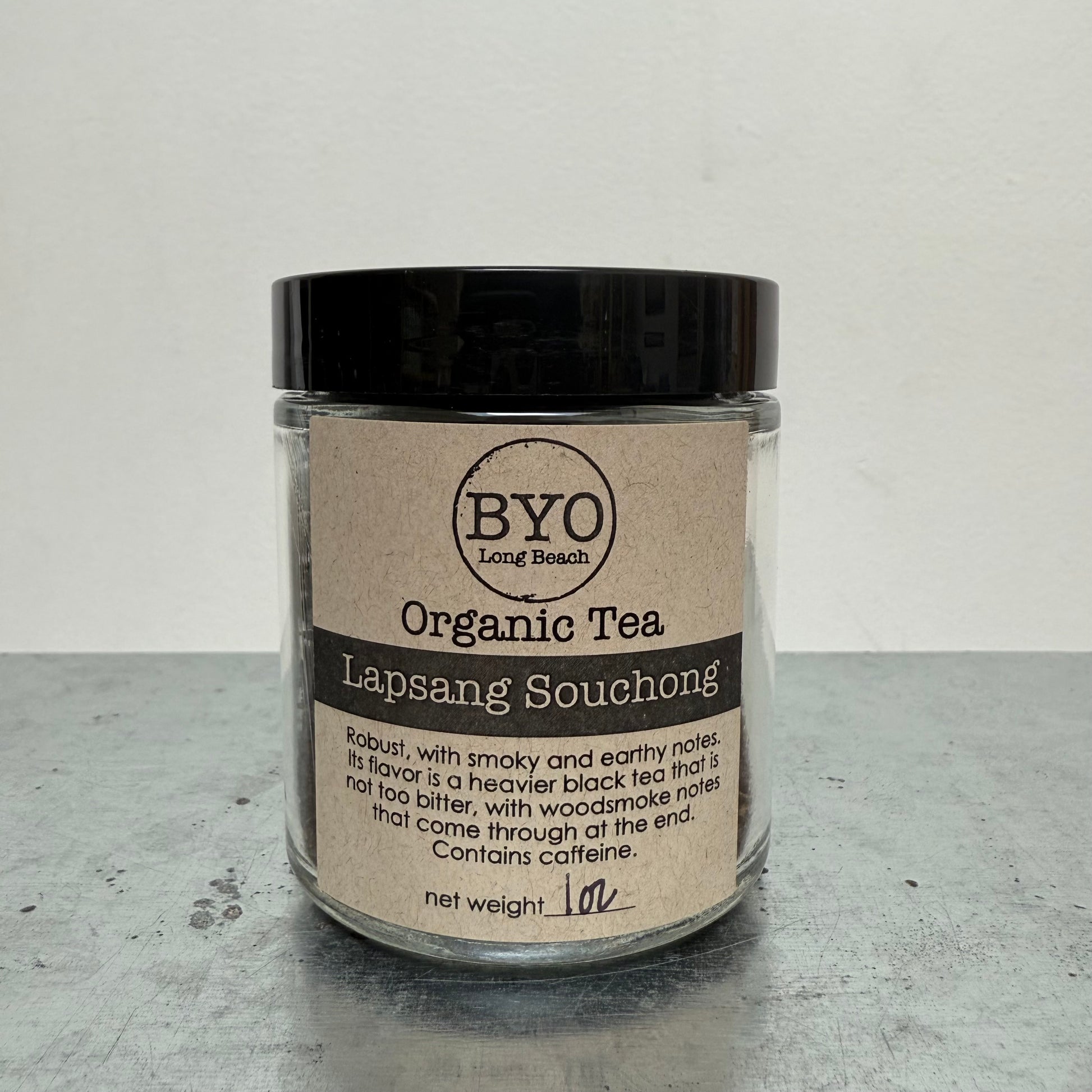 Jar of Organic Tea Lapsang Souchong with a black lid on a gray surface