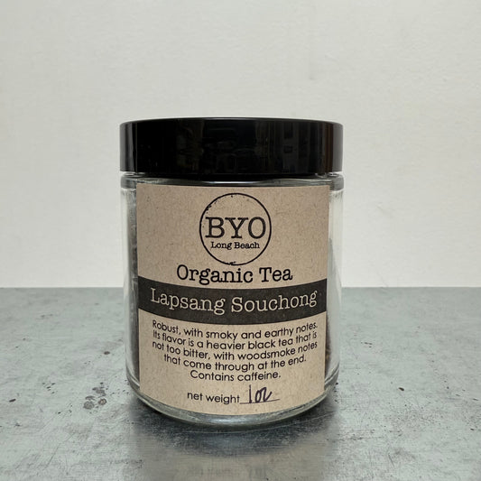 Jar of Organic Tea Lapsang Souchong with a black lid on a gray surface