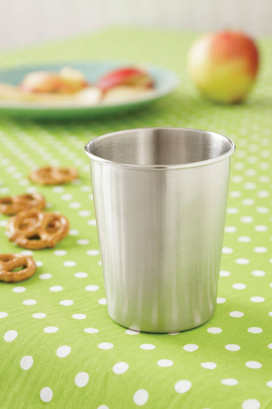 Stainless steel cup on a green polka dot tablecloth with snacks in the background