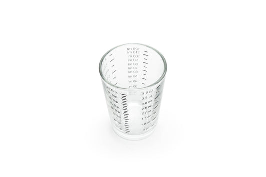 Clear glass measuring cup with measurement markings on a white background