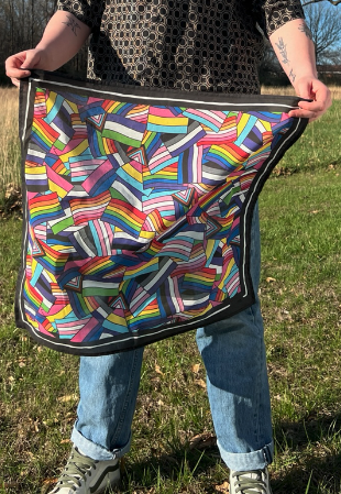 Person holding a colorful patterned bandana outdoors