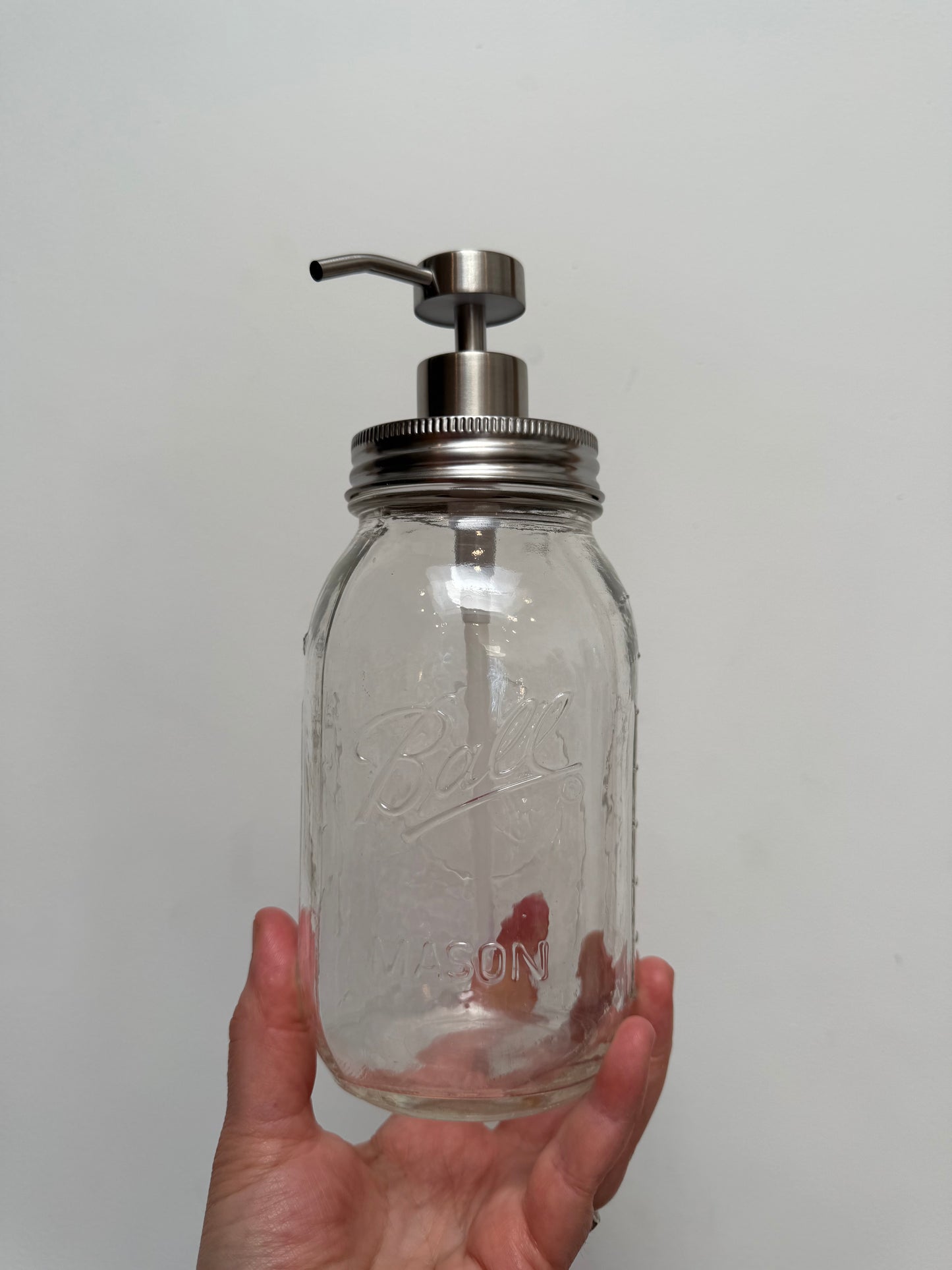 Hand holding quart mason jar with stainless steel regular pump top