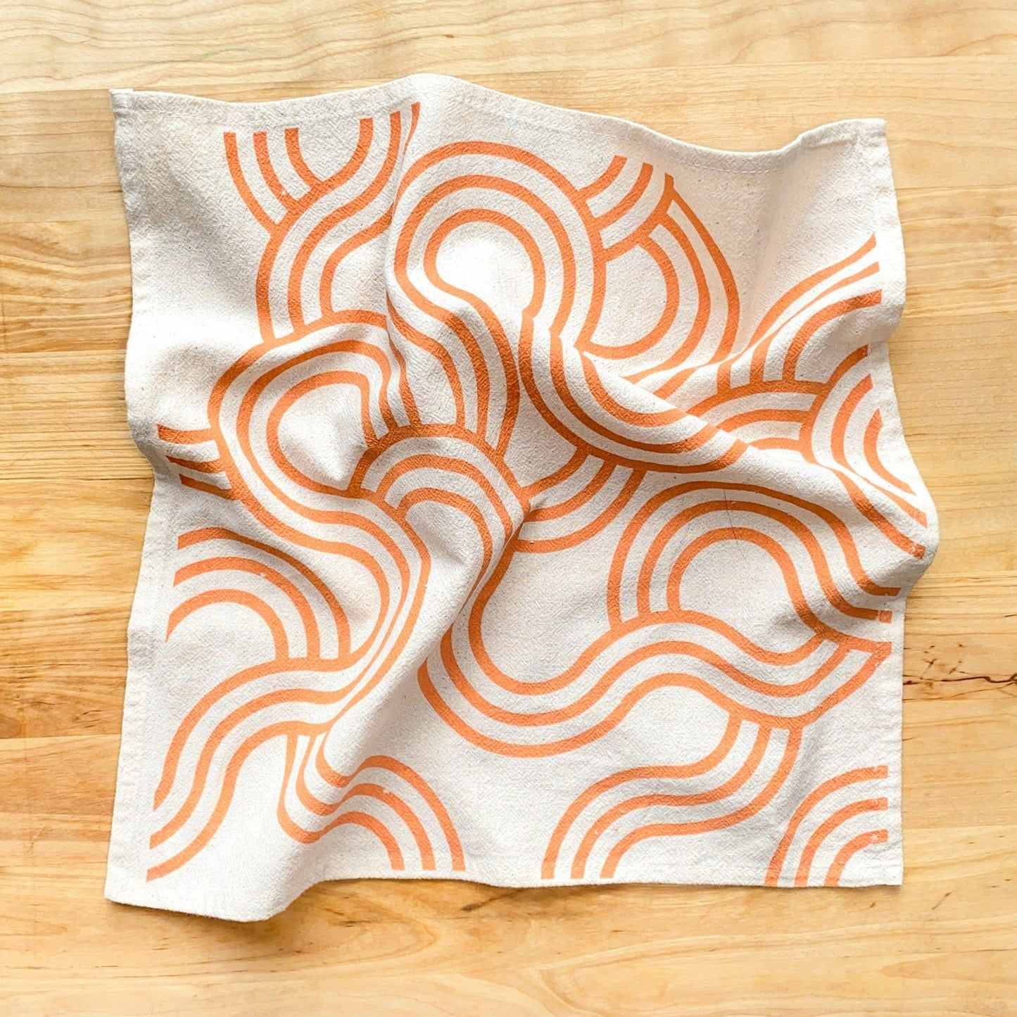 Fabric with orange wavy pattern on a wooden surface