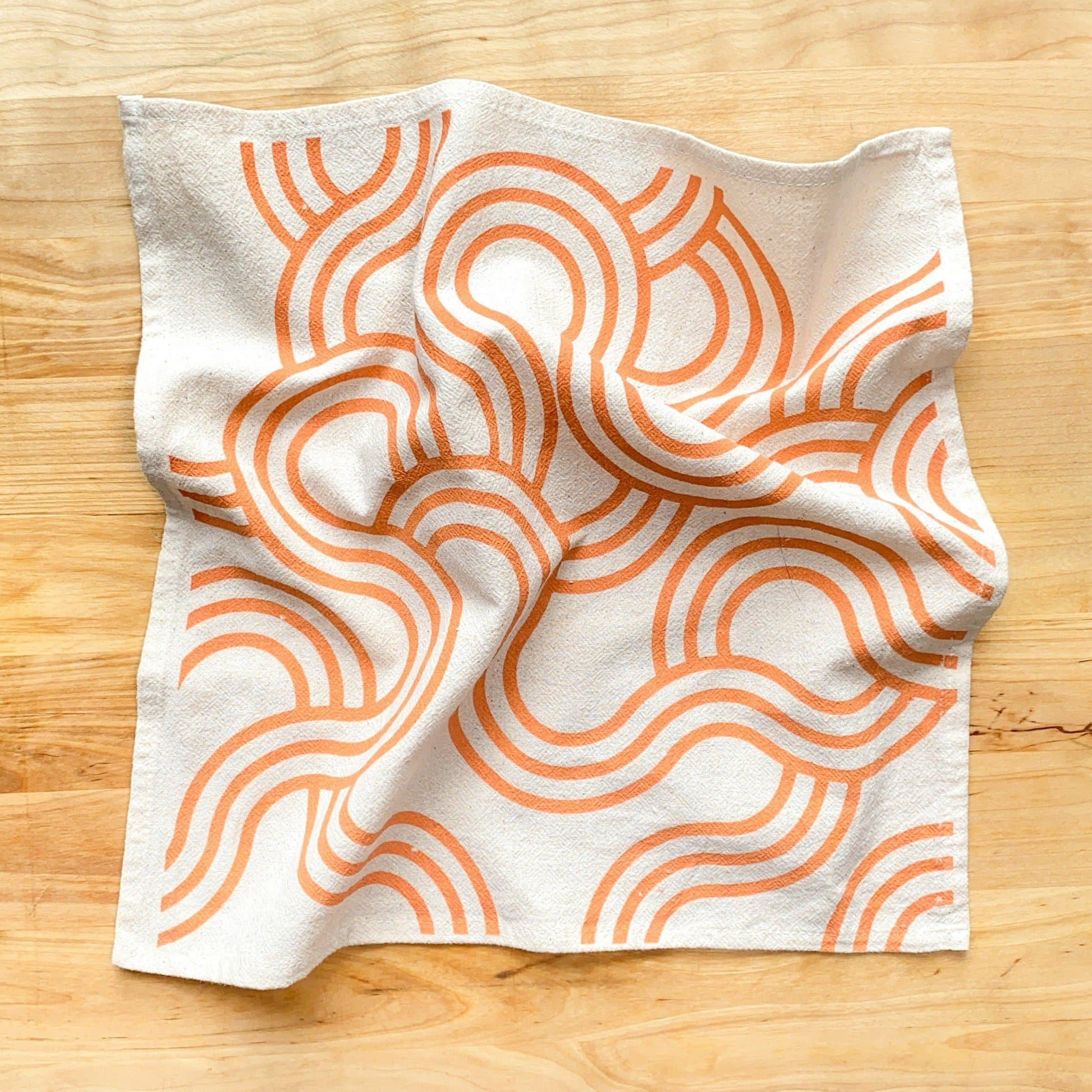 Fabric with orange wavy pattern on a wooden surface