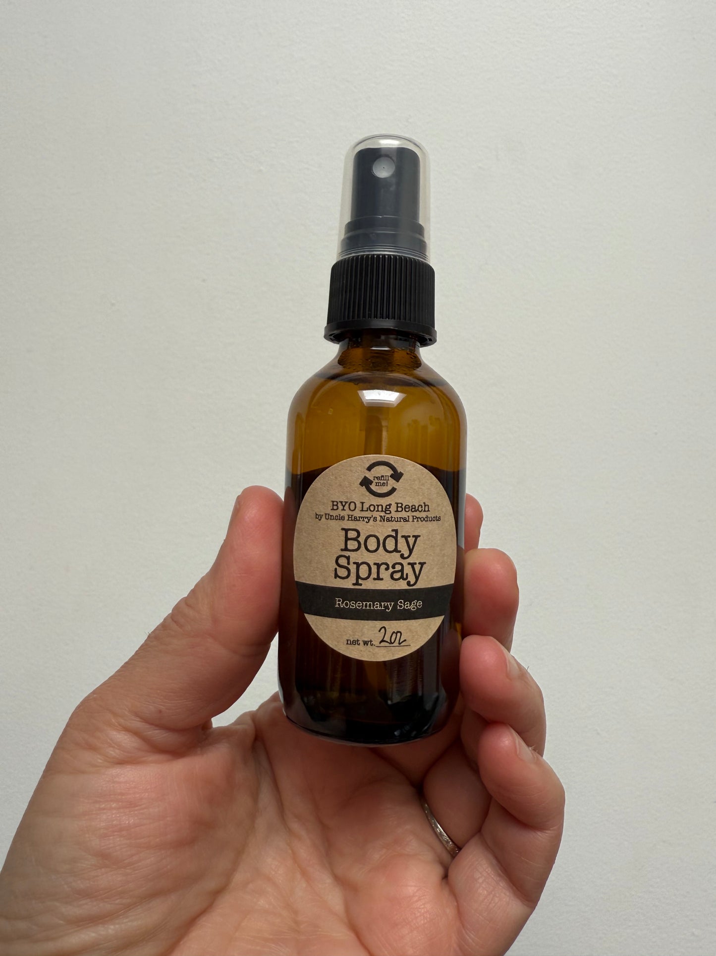 Hand holding amber glass spray bottle with label 