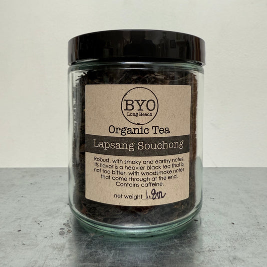 Glass jar of organic Lapsang Souchong tea with a label on a gray surface.