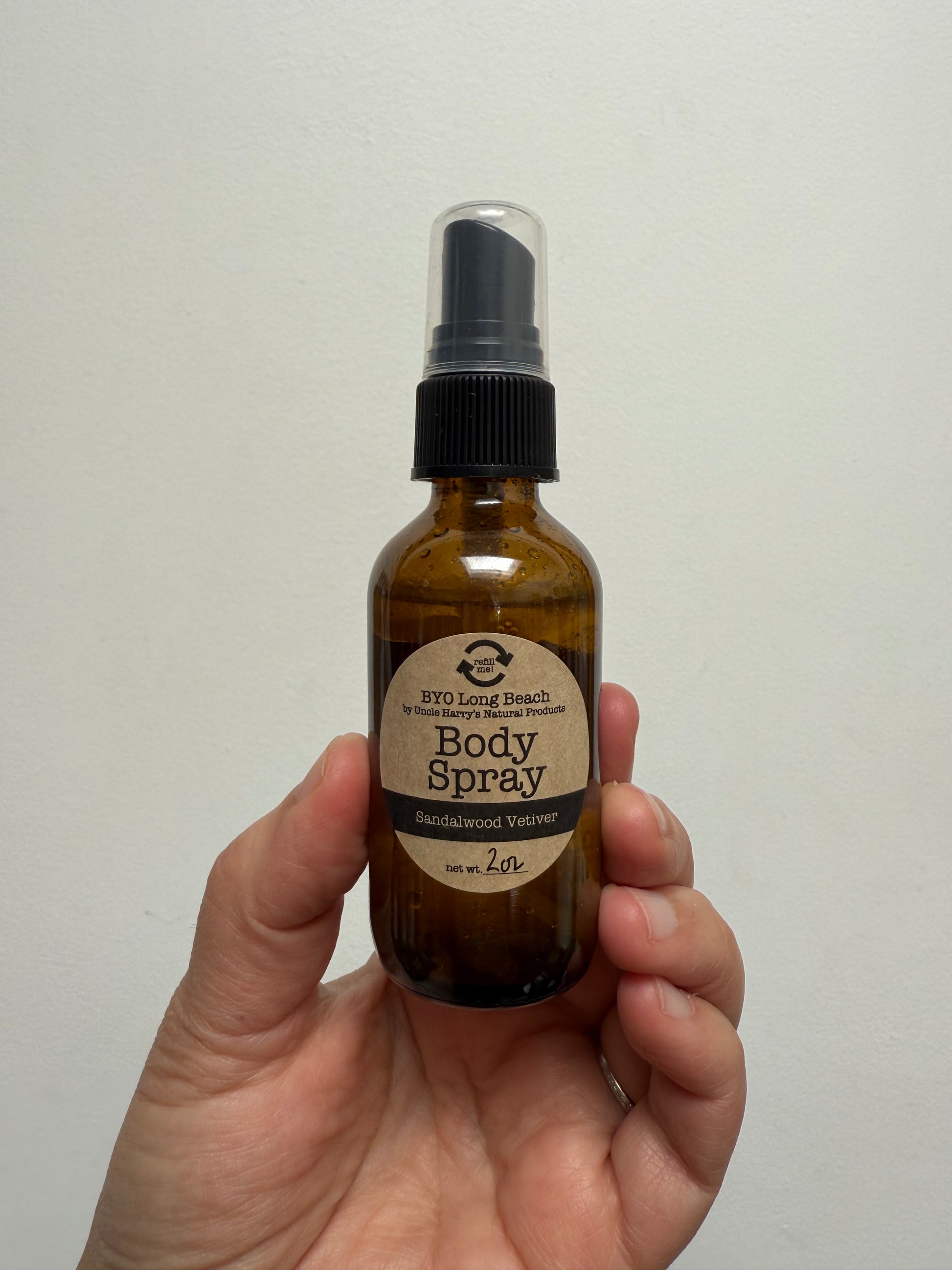 Hand holding amber glass spray bottle with label 