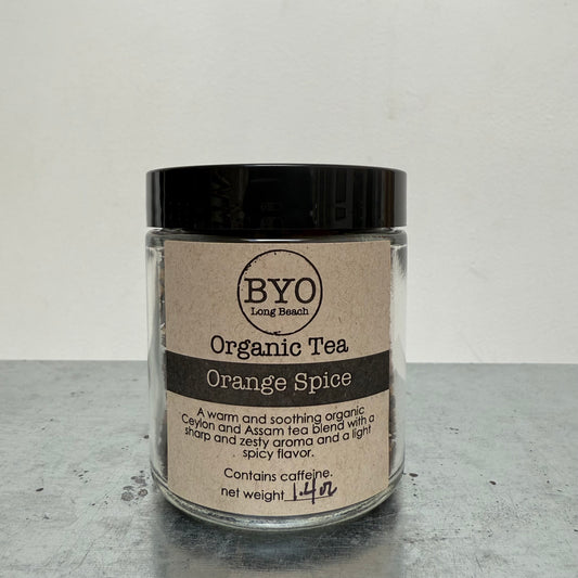 Glass jar of Organic Tea with a black lid on a gray surface