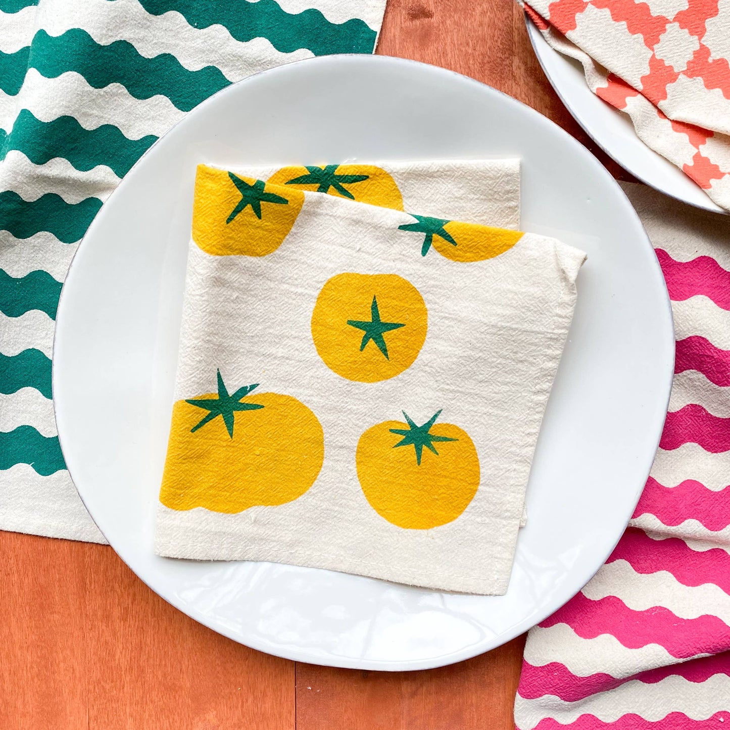 Napkin with yellow tomato design on a white plate against a colorful background