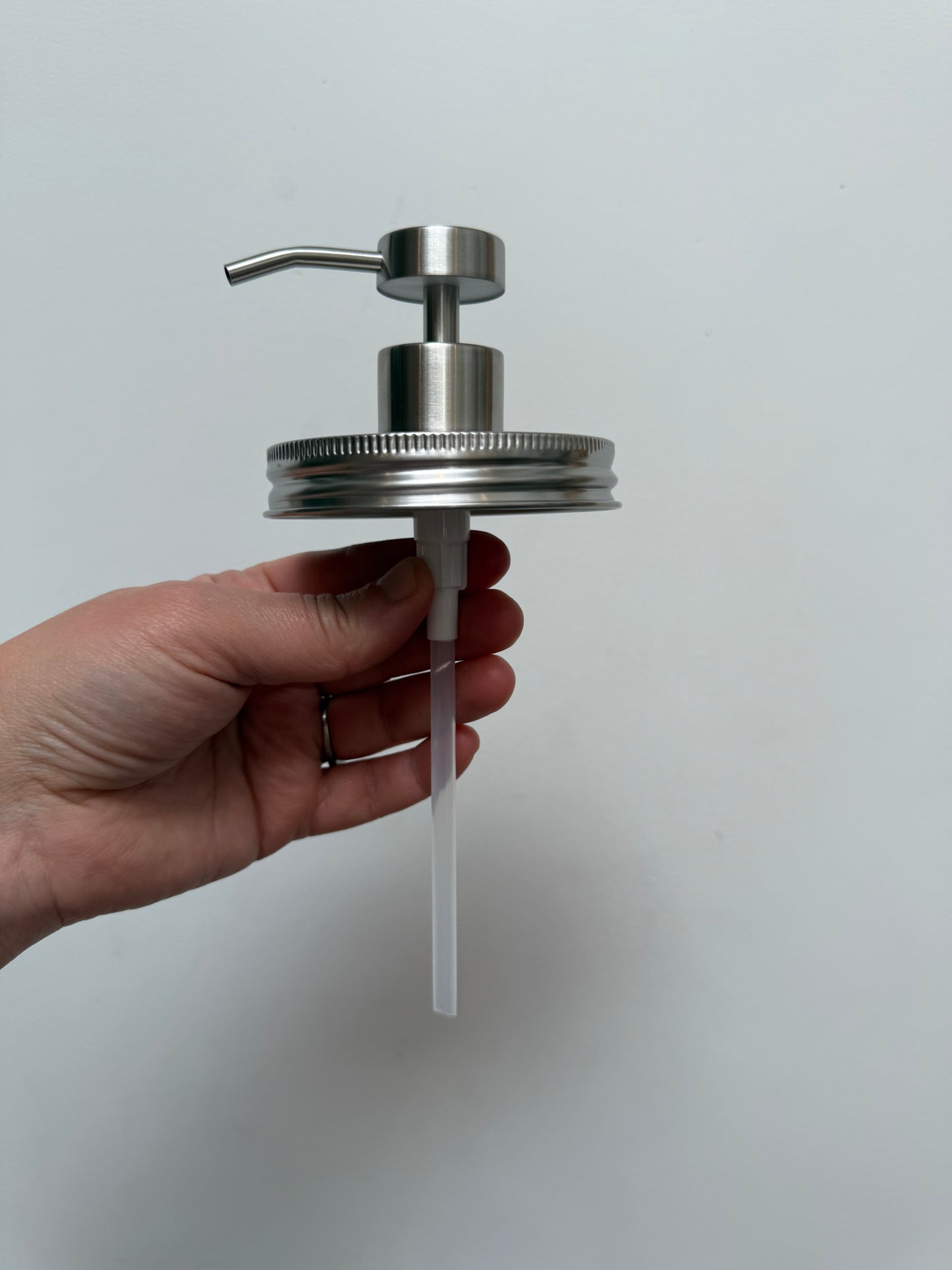 Hand holding stainless steel wide mouth pump top without jar