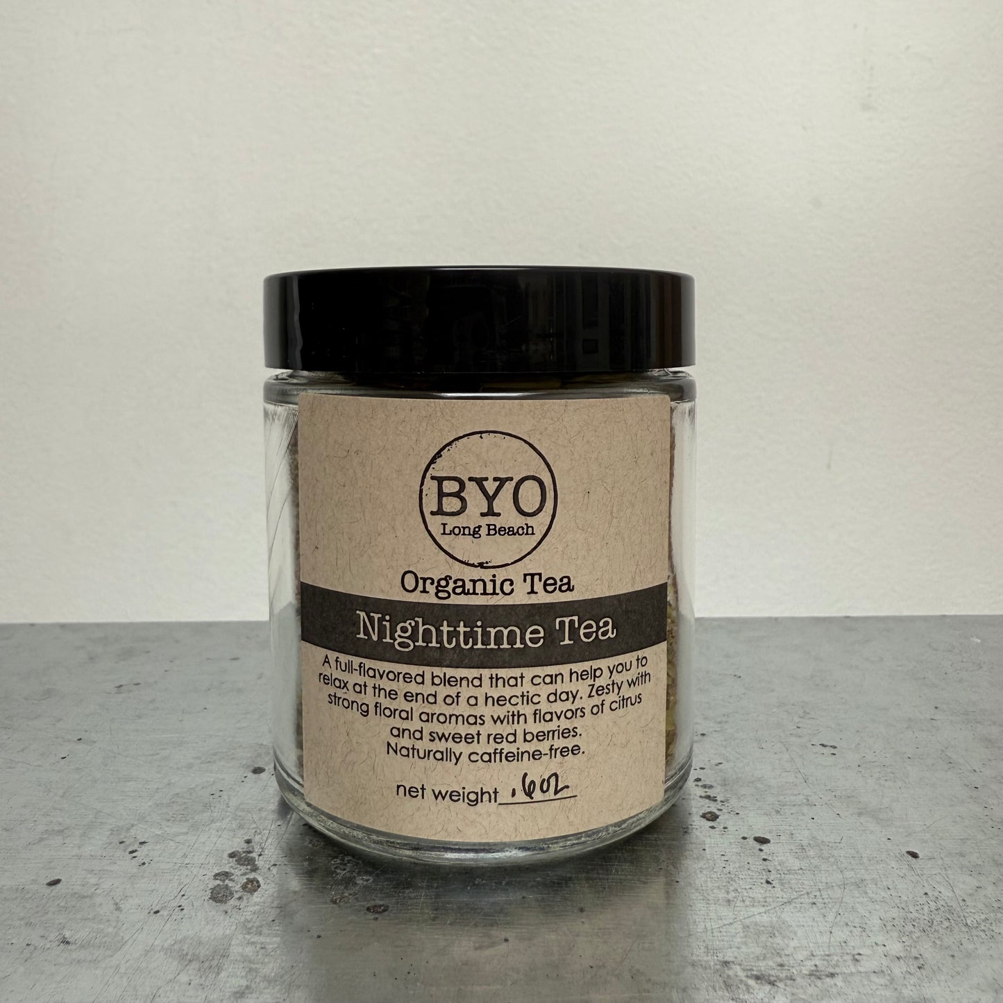 Glass jar of Organic Tea Nighttime Tea with a black lid on a gray surface.