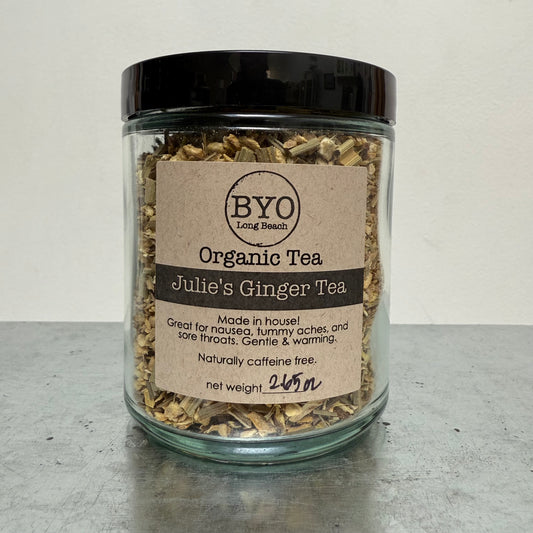 Jar of organic tea labeled 'Julie's Ginger Tea' by BYO on a gray surface.