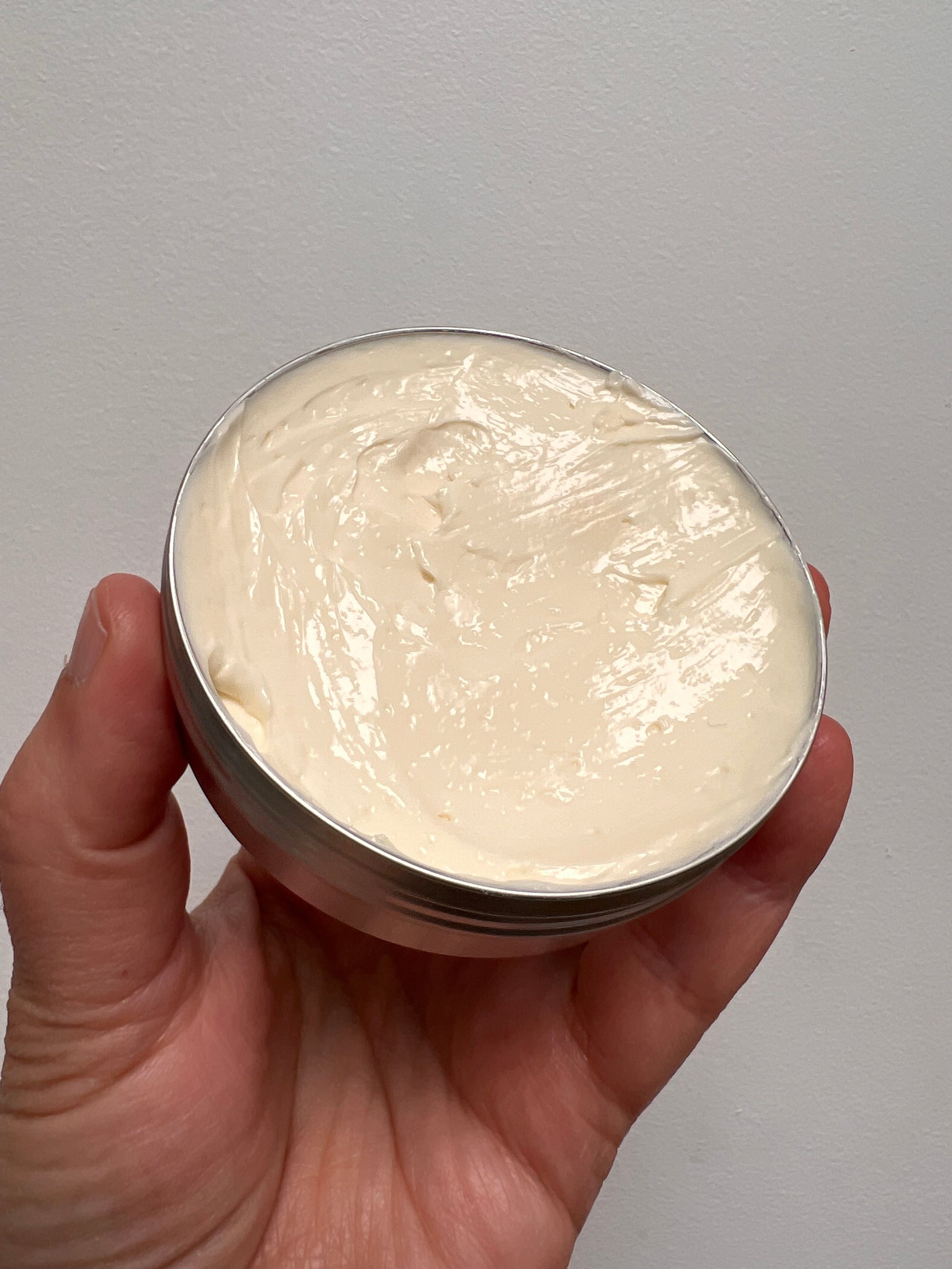 Lid off showing the facial cream which is white and thick