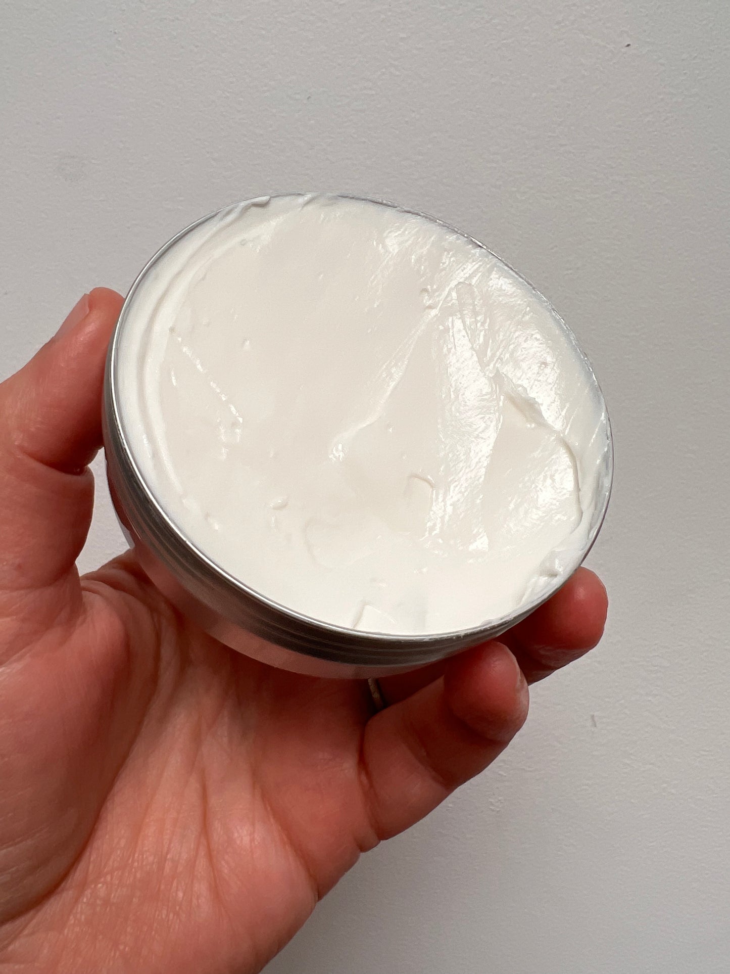 Lid off the tin showing the facial cream which is thick and white.