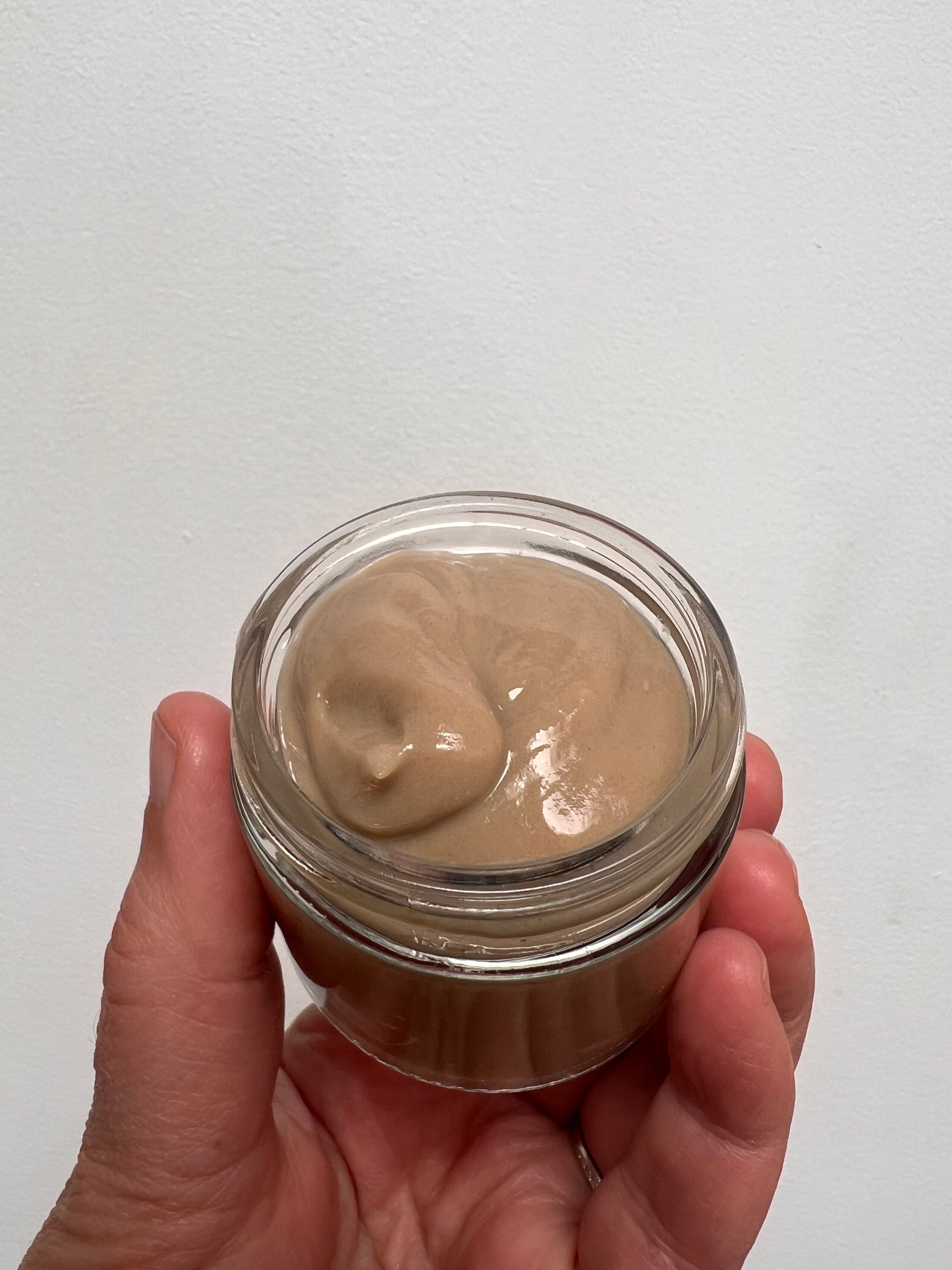 Glass jar showing texture of hair gel which is light brown and a creamy thick texture.