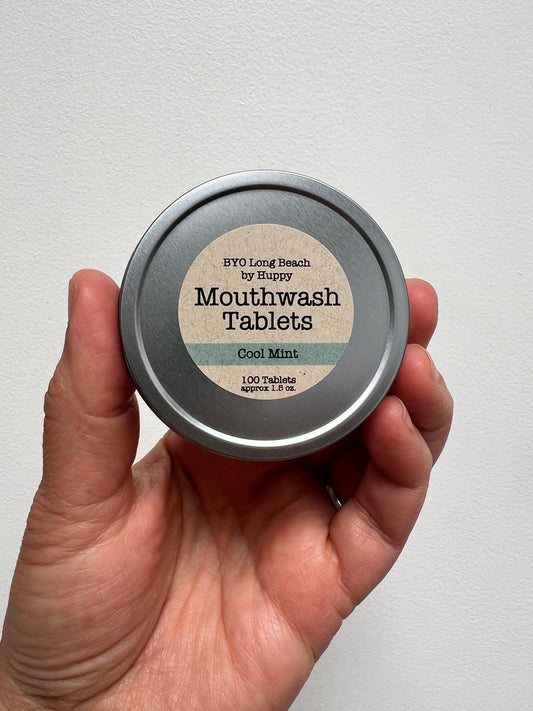 hand holding a metal tin with label of mouthwash tablets